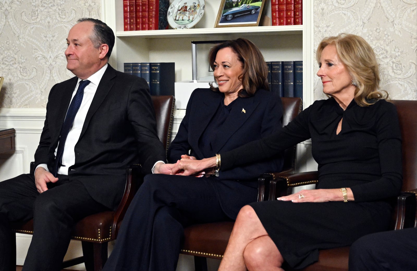 Second gentleman Doug Emhoff, left, and first lady Jill Biden, right, hold hands with Vice President Kamala Harris as President Joe Biden speaks from the Oval Office of the White House as he gives his farewell address Wednesday, Jan. 15, 2025, in Washington. (Mandel Ngan/Pool via AP)