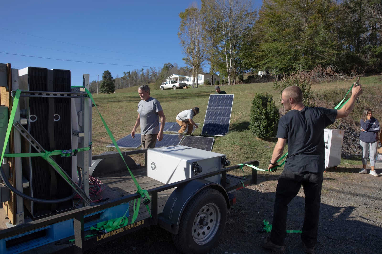 Hayden Wilson, left, Jonathan Bowen, second from left, Alexander Pellersels second from right, and Henry Kovacs, right, install a mobile power system for a resource hub in Tipton Hill, N.C. on Oct. 9, 2024. (AP Photo/Gabriela Aoun Angueria)