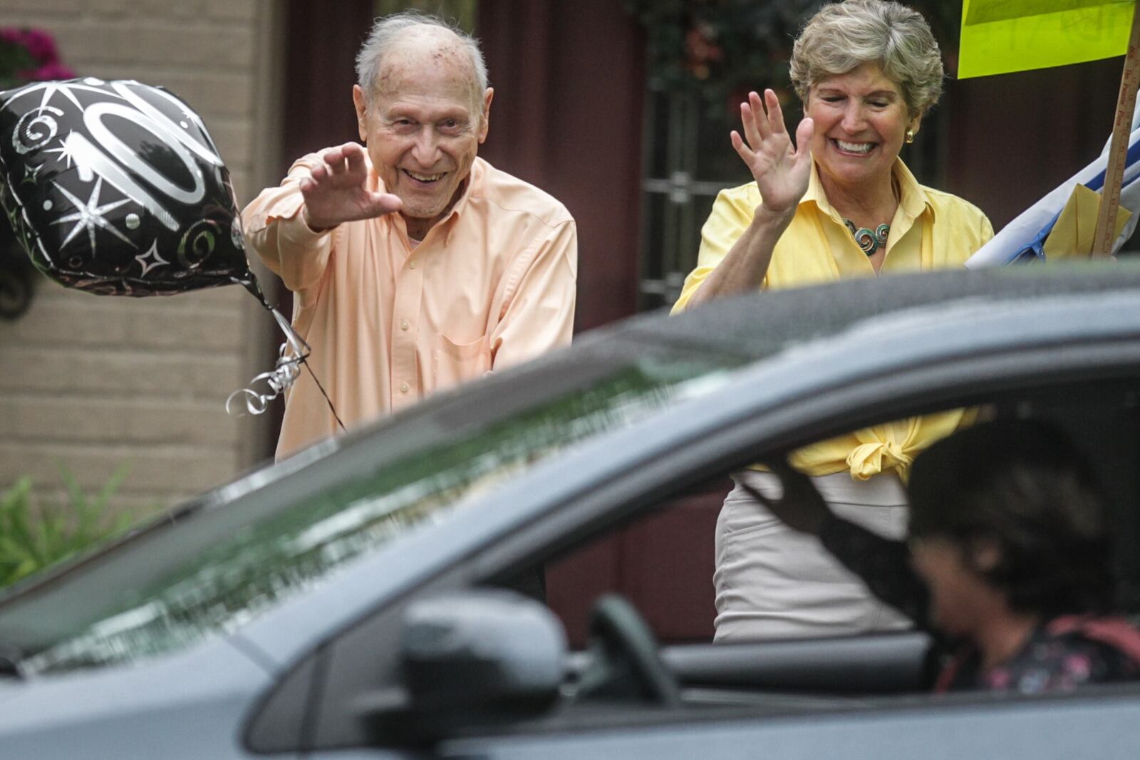 Jim Taylor and his wife, Lynn, wave to well wishers. The coronavirus pandemic means that Jim Taylor's 100th birthday party had to be put on hold, but friends and neighbors celebrated the World War II veteran's milestone with a caravan Monday, May 18, 2020. JIM NOELKER / STAFF