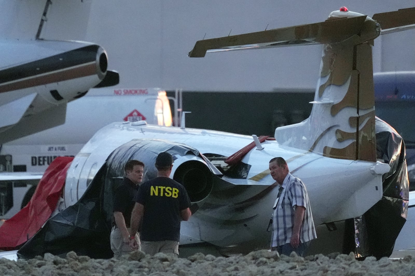 Investigators look at a crashed Learjet at Scottsdale Airport after it collided with a parked plane Monday, Feb. 10, 2025, in Scottsdale, Ariz. (AP Photo/Ross D. Franklin)