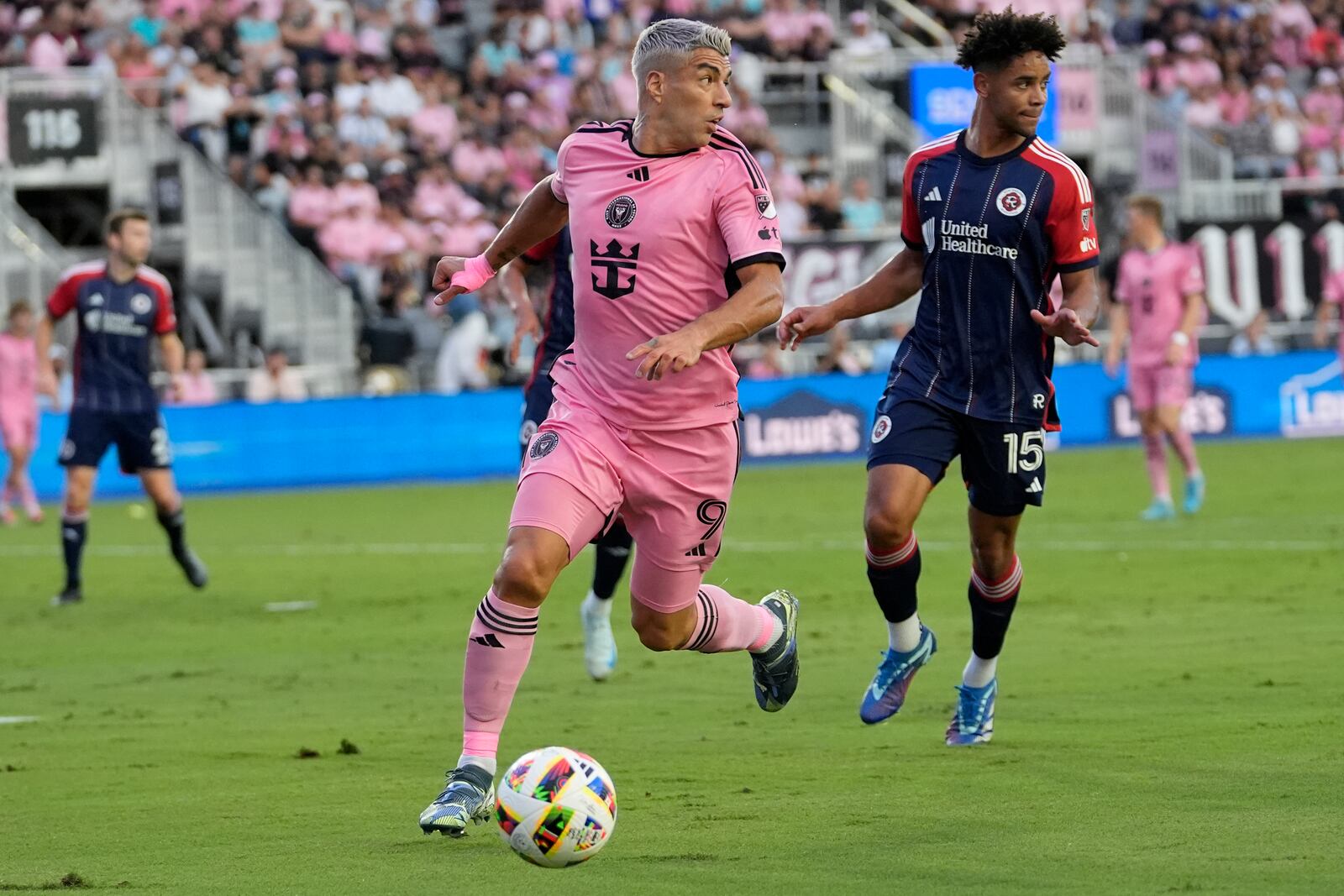 Inter Miami forward Luis Suarez (9) runs with the ball as New England Revolution midfielder Brandon Bye (15) defends during the first half of an MLS soccer match, Saturday, Oct. 19, 2024, in Fort Lauderdale, Fla. (AP Photo/Lynne Sladky)