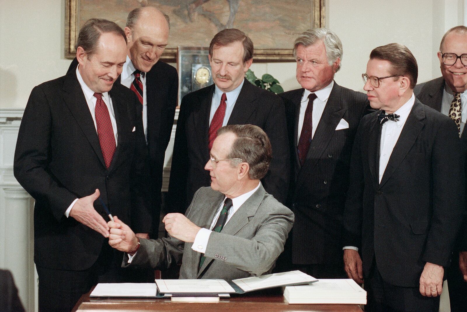 FILE - President George H. Bush hands a pen to Attorney General Dick Thornburgh, left, after he signed into law an immigration bill, Nov. 29, 1990, in Washington at the White House. From left often Thornburgh are Sen. Alan Simpson, R-Wyo., Rep. Bruce Morrison, D-Conn., Edward Kennedy, D-Mass., and Sen. Paul Simon, D-Ill. The last extensive package came under President Ronald Reagan in 1986, and President George H.W. Bush signed a more limited effort four years later. Simpson has died at age 93. (AP Photo/Marcy Nighswander, File)