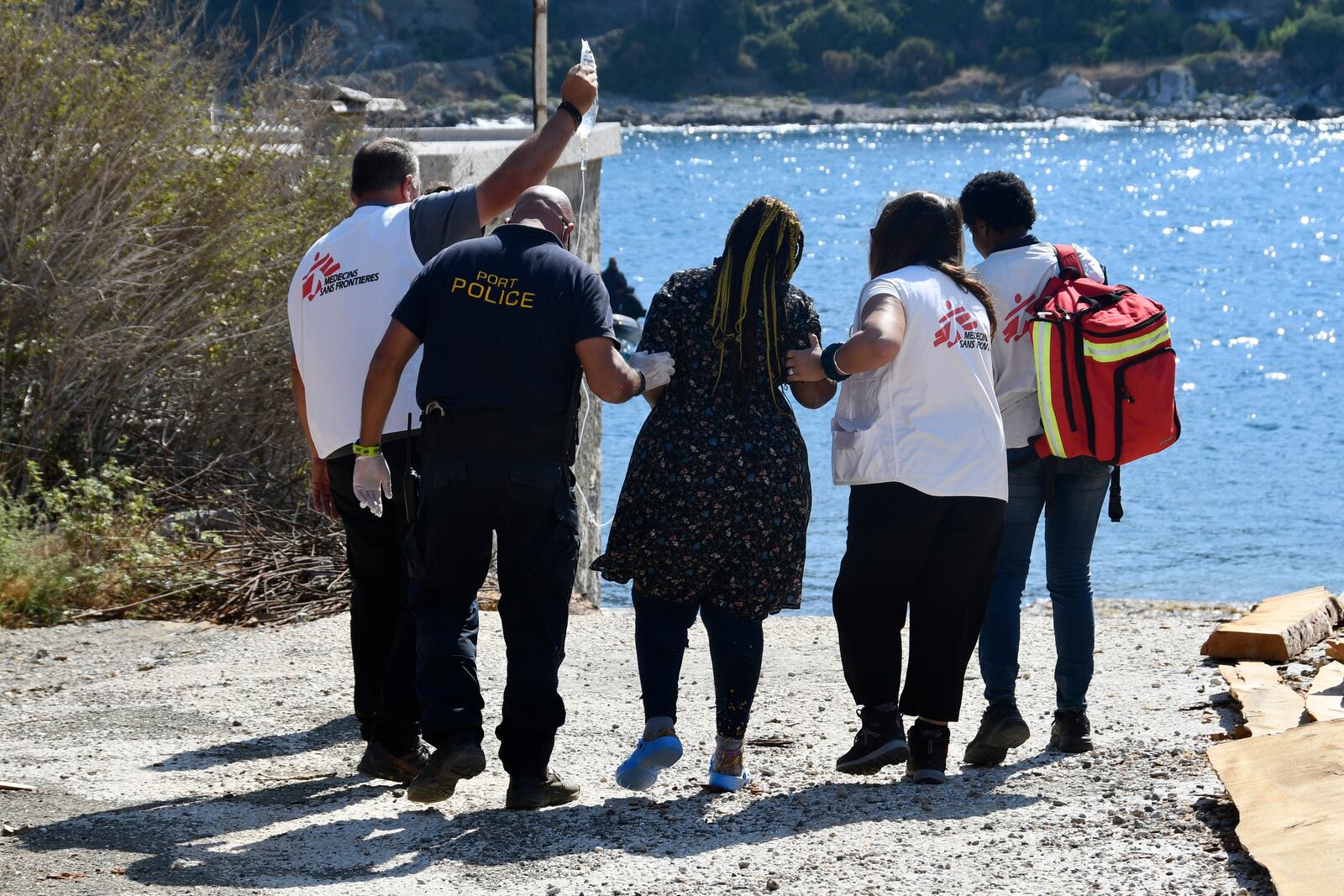 Members of Doctors Without Borders and a coast guard officer help a pregnant woman who survived after a boat carrying migrants ran into trouble off the coast of the eastern Aegean Sea island of Samos, Greece, on Monday, Sept. 23, 2024. (AP Photo/Michael Svarnias)