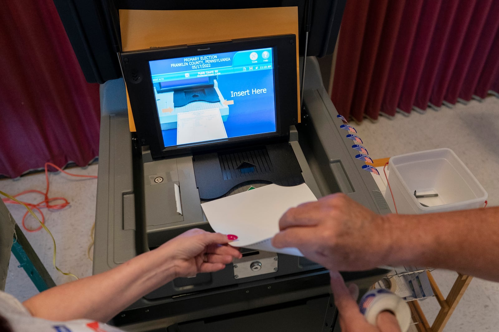 FILE - A polling judge, right, helps guide a voter's ballot into a voting machine during the Pennsylvania primary election, at Mont Alto United Methodist Church in Alto, Pa., on May 17, 2022. (AP Photo/Carolyn Kaster, File)