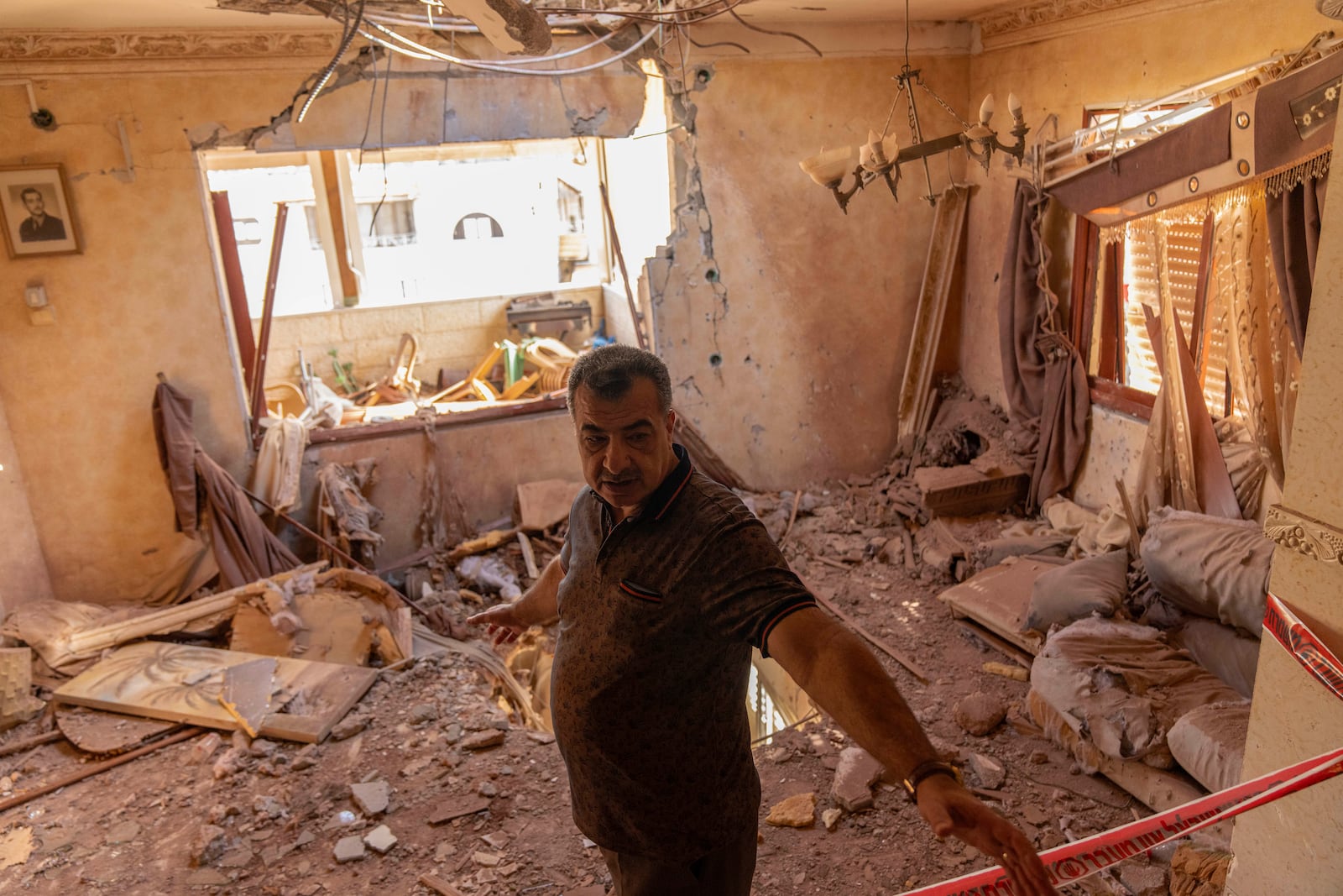 A local resident stands next to debris inside his house after it was struck by projectiles fired from Lebanon in Kfar Yasif, north west Israel, Saturday, Nov. 9, 2024. (AP Photo/Francisco Seco)