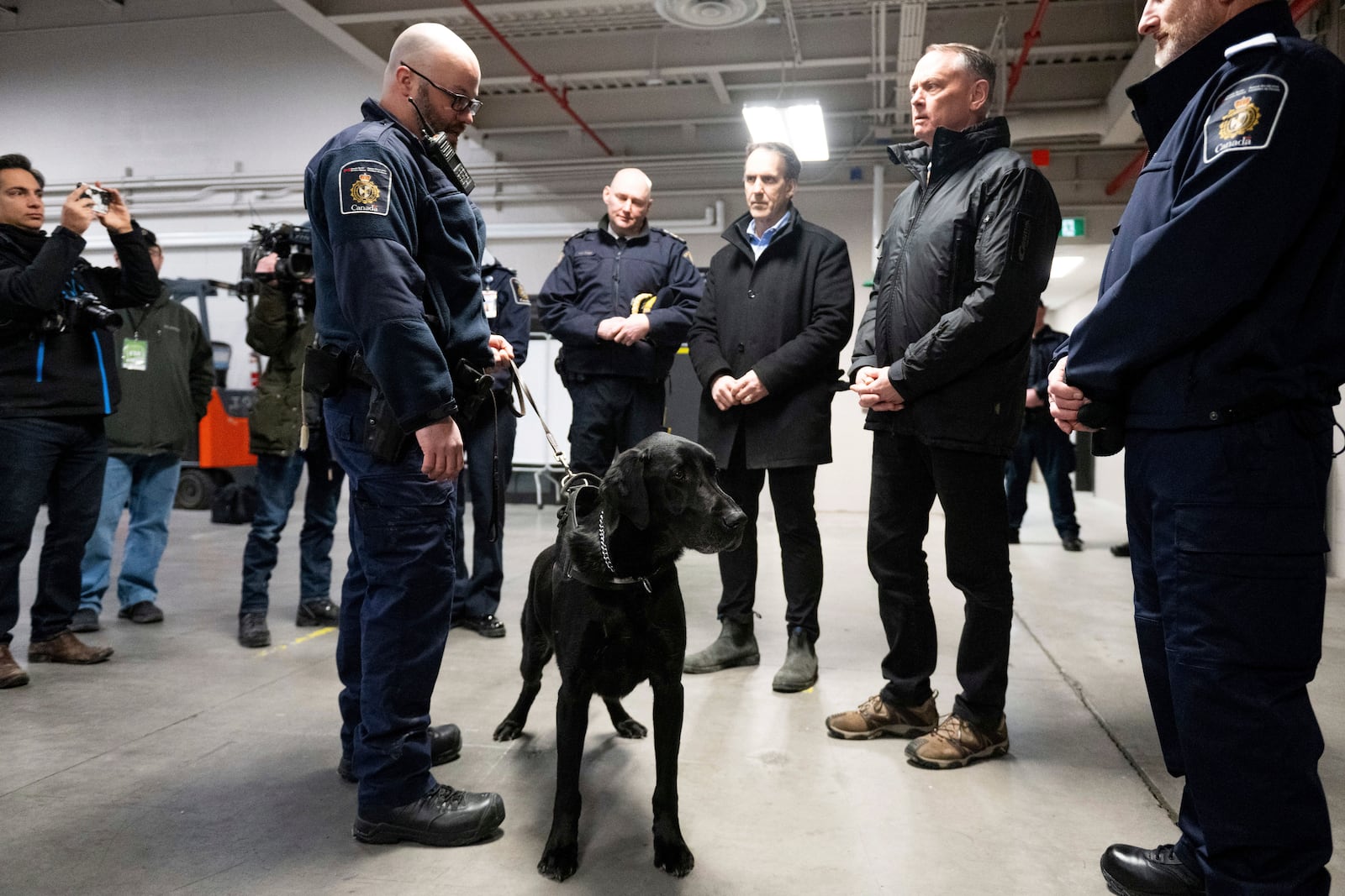 Denver, a Canada Border Services Agency narcotics detection dog, is seen during a tour of the CBSA Lansdowne port of entry in Lansdowne, Ontario, with Minister of Public Safety David McGuinty, right, and Canada's fentanyl czar Kevin Brosseau, center right, Wednesday, Feb. 12, 2025. (Spencer Colby/The Canadian Press via AP)