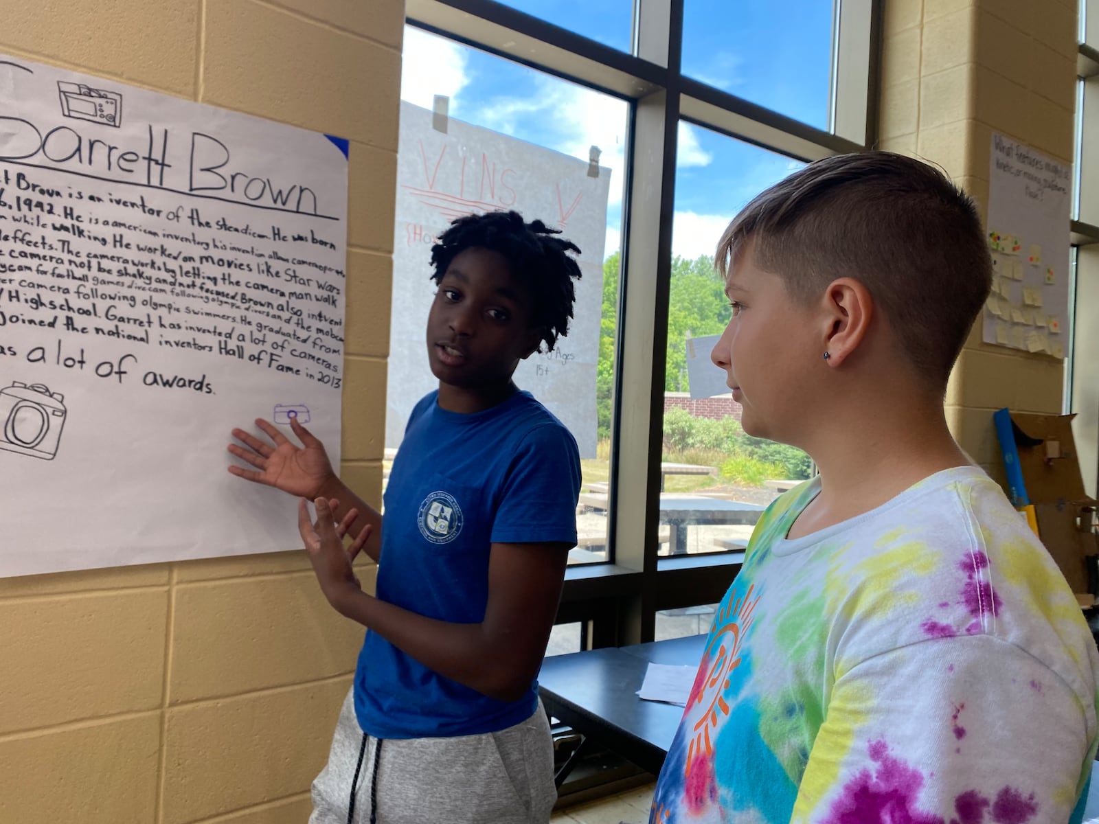 Lamar Lynch, an eighth grader in Huber Heights schools, presents a poster he made during STEM camp at Weisenborn Middle School while Blake Beeching, another eighth grader on Lynch's team who also worked on the project, looks on. Eileen McClory/ staff