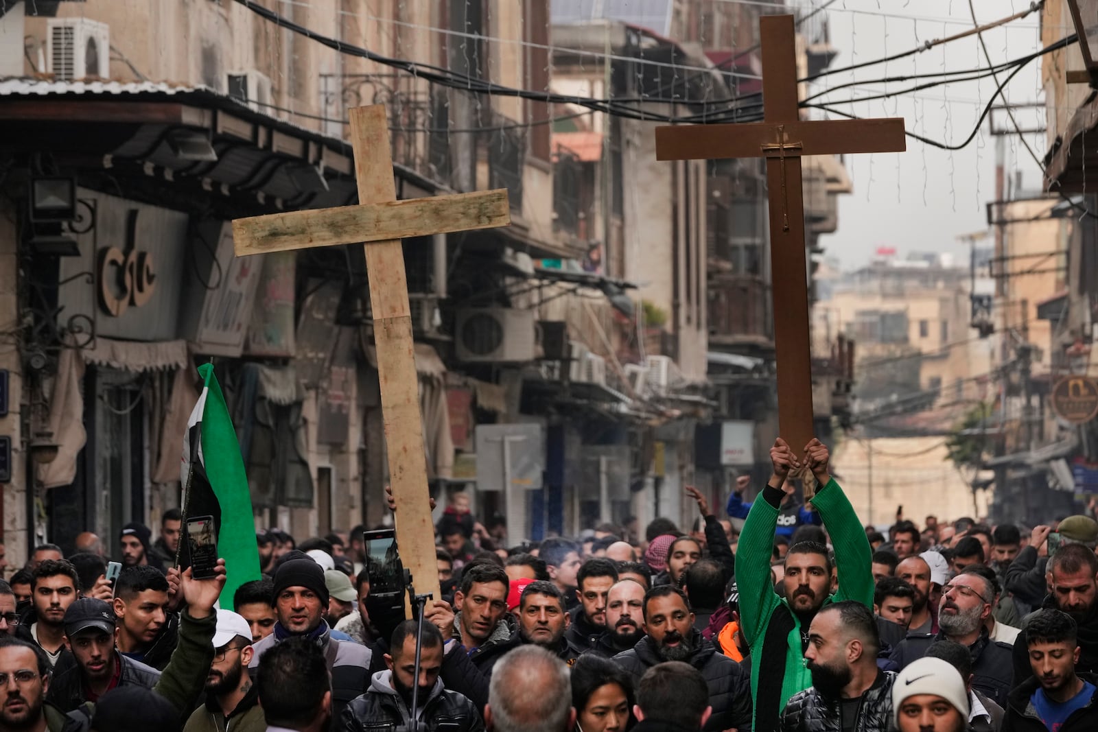 Syrian Christians hold up crosses and shout slogans in Damascus, Syria, Tuesday, Dec. 24, 2024 as they march during a protest after a Christmas tree was set on fire in Hamah city on Sunday. (AP Photo/Hussein Malla)