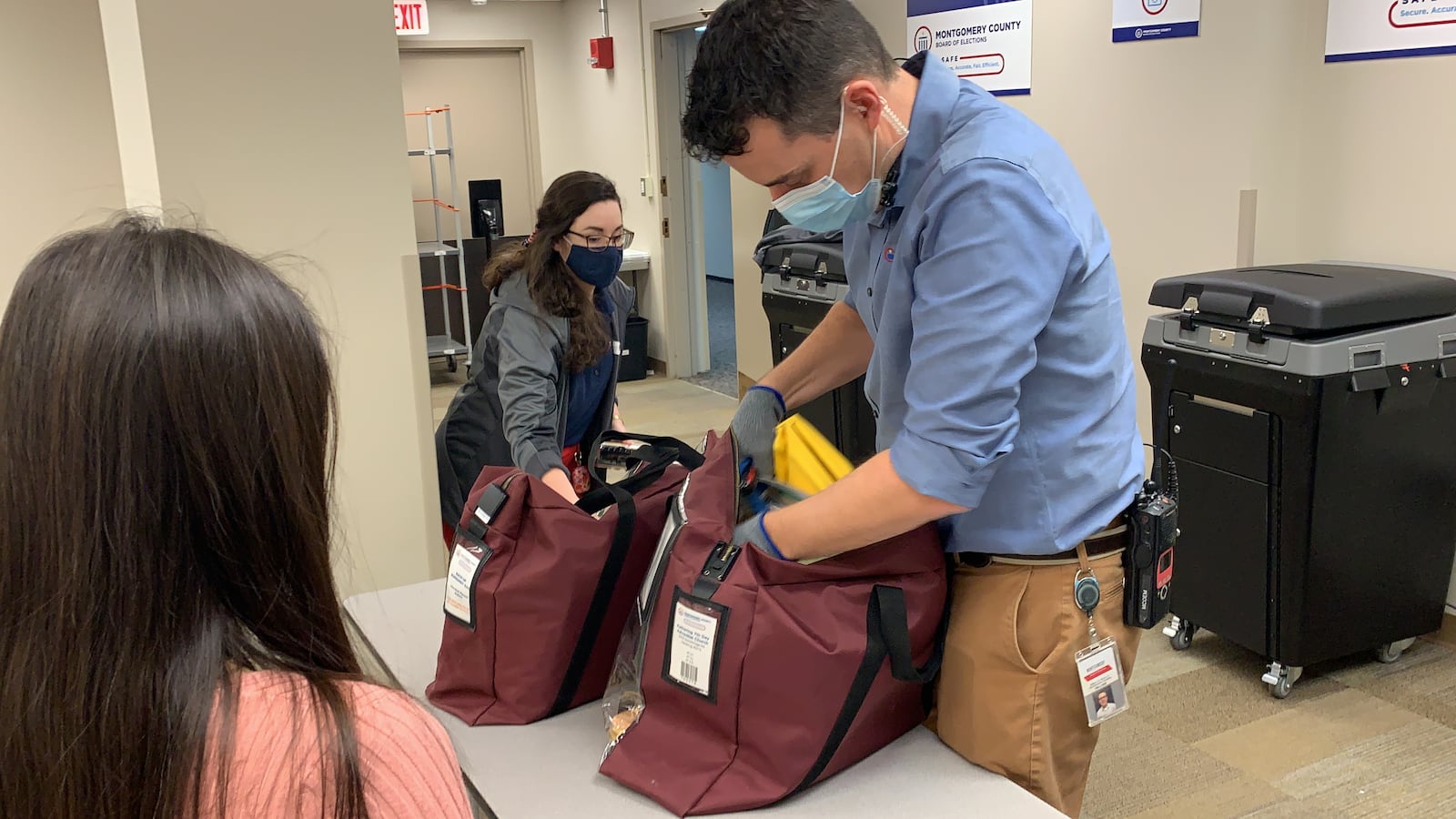 A Montgomery County Board of Elections worker breaks the seal on a bag containing elections materials and hands it to other workers so votes can be counted and other material sorted.