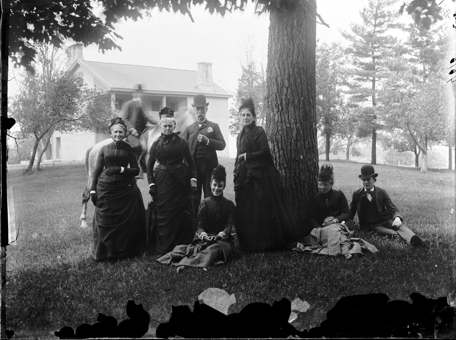 A gathering occurs beneath a tree on the grounds of the Patterson Homestead. Note the blurred horseback rider. Photo courtesy of Dayton History