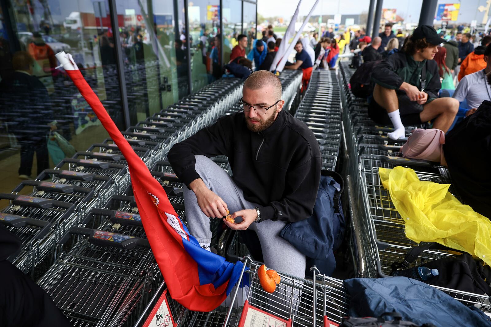 A student, who is on a march to Belgrade for a joint protest, sits in a shopping cart in front of a store in Nova Pazova, Serbia, Friday, March 14, 2025. (AP Photo/Armin Durgut)