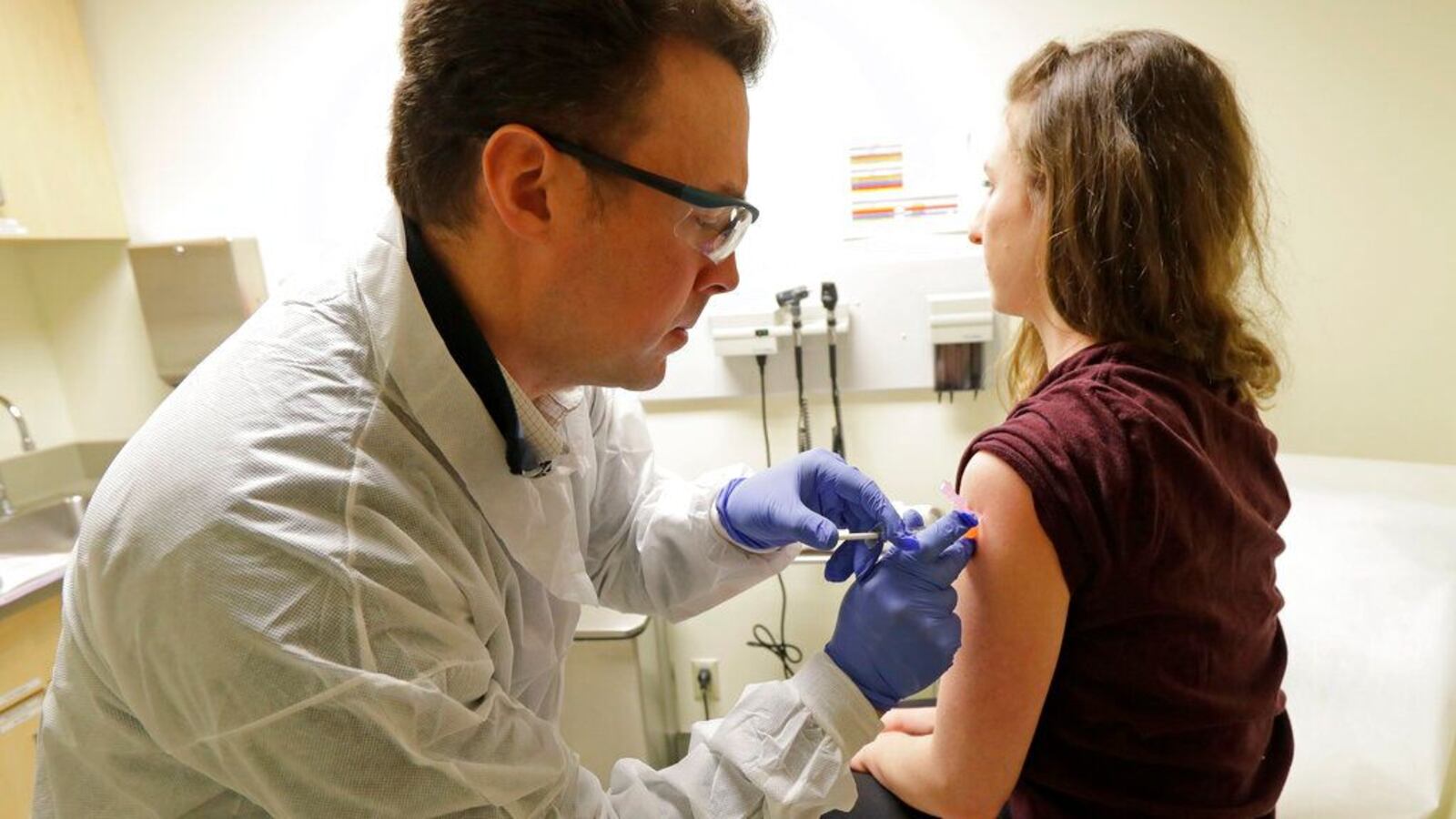 In this March 16, 2020, file photo, pharmacist Michael Witte, left, gives Rebecca Sirull a shot in the first-stage safety study clinical trial of a potential vaccine for COVID-19, the disease caused by the new coronavirus, Monday, March 16, 2020, at the Kaiser Permanente Washington Health Research Institute in Seattle. Sirull is the third patient to receive the shot in the study. Researchers say the first phase of human clinical trials for a COVID-19 vaccine in healthy volunteers in the Pittsburgh area could start in the coming months.