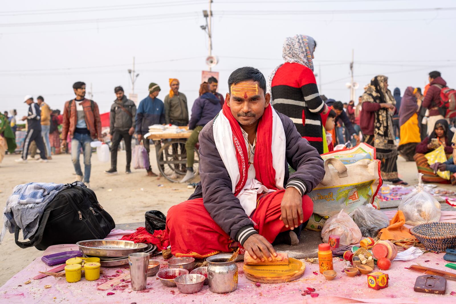 A Hindu priest, who puts sacred marks on devotees' foreheads, sits at his stall at the confluence of the Ganges, the Yamuna, and the Saraswati rivers during the 45-day-long Maha Kumbh festival in Prayagraj, India, Tuesday, Jan. 14, 2025. (AP Photo/Ashwini Bhatia)