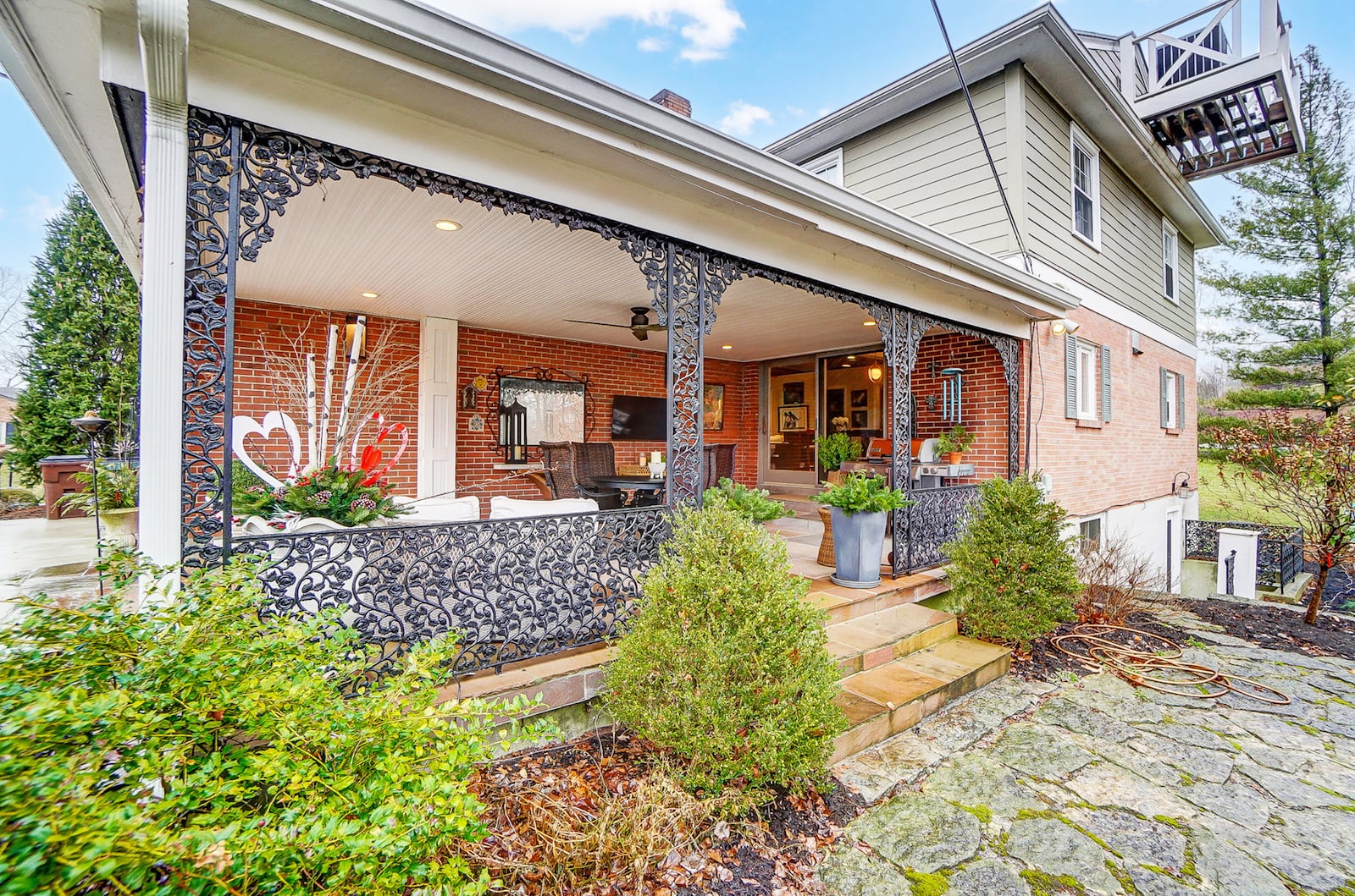 The flagstone rear covered patio has an outdoor television and wrought iron railings.