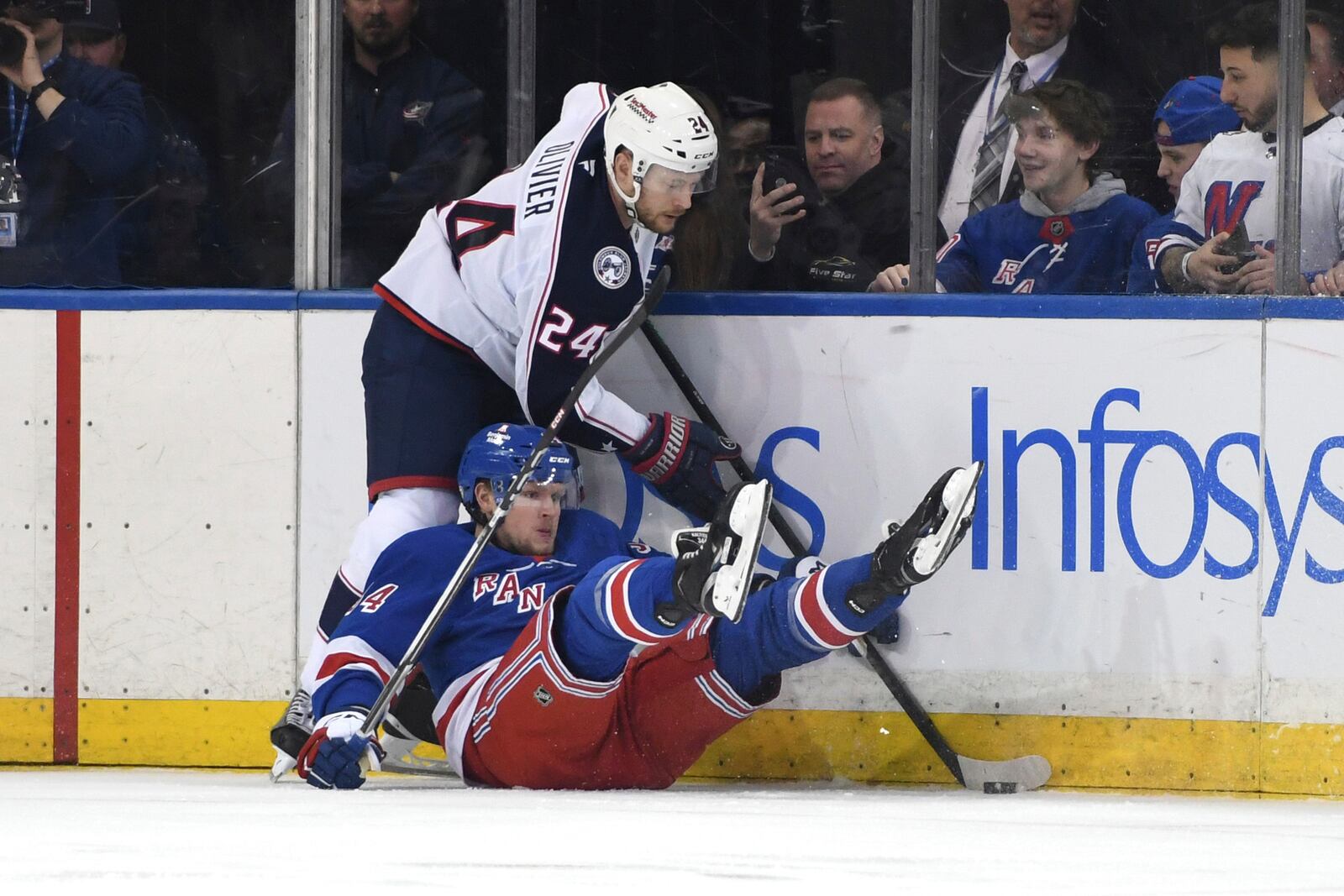 New York Rangers' Arthur Kaliyev, below, falls while attempting to steal the puck from Columbus Blue Jackets' Mathieu Olivier, above, during the first period of an NHL hockey game Saturday, Jan. 18, 2025, in New York. (AP Photo/Pamela Smith)