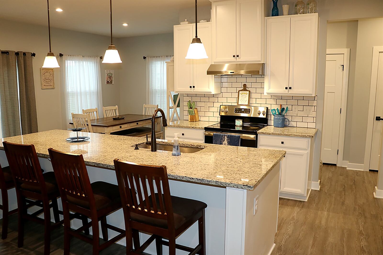 The kitchen has a single sink and dishwasher. Hanging lights accent the light granite countertops. Off to one side, counter space offers a buffet or coffee station, and 42-inch shaker cabinetry fills two separate walls spaces. CONTRIBUTED PHOTO BY KATHY TYLER