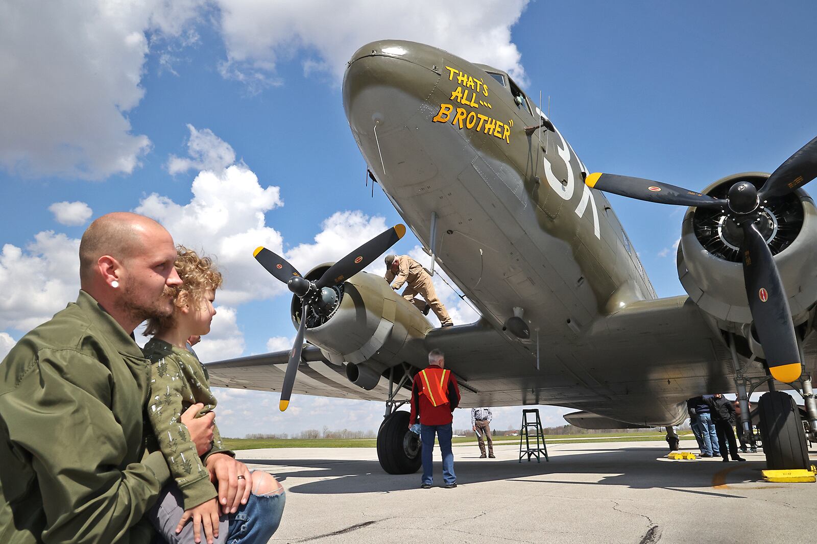 Jonathan Dalton and his son, Rowan, watch as the flight crew of the "That's All, Brother," a C-47 airplane refuel the aircraft Monday at Grimes Field in Urbana. In 1944, the plane led over 800 C-47's that dropped over 13,000 paratroopers into battle as part of D-Day. The C-47 was on view at Grimes Field before traveling to the National Museum of the United States Air Force on Tuesday. BILL LACKEY/STAFF