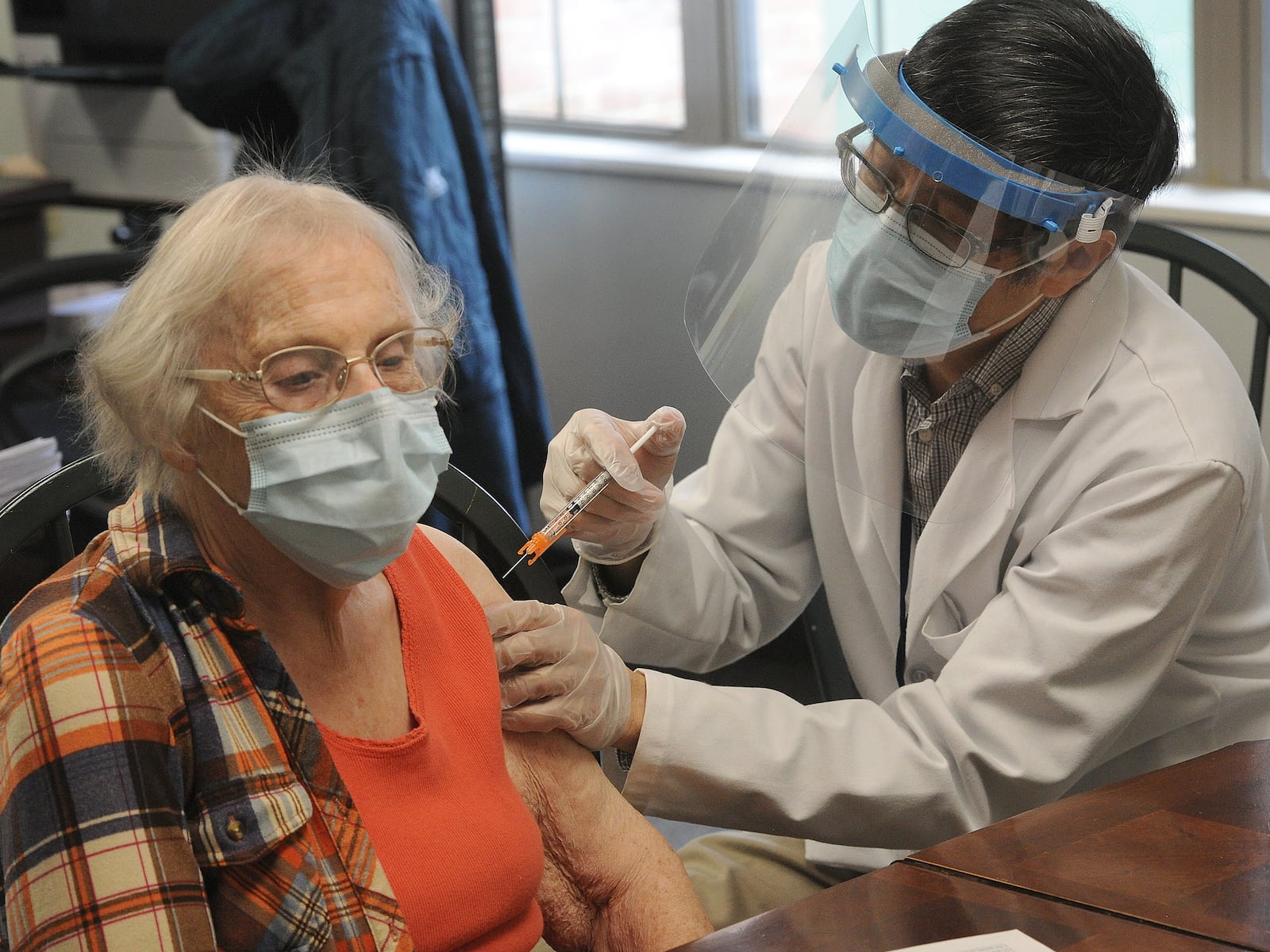 Jean Rowe, a resident of AHEPA 113 Senior Apartments, receives her Coronavirus vaccine from Tom Wong, Friday, Jan. 8, 2021