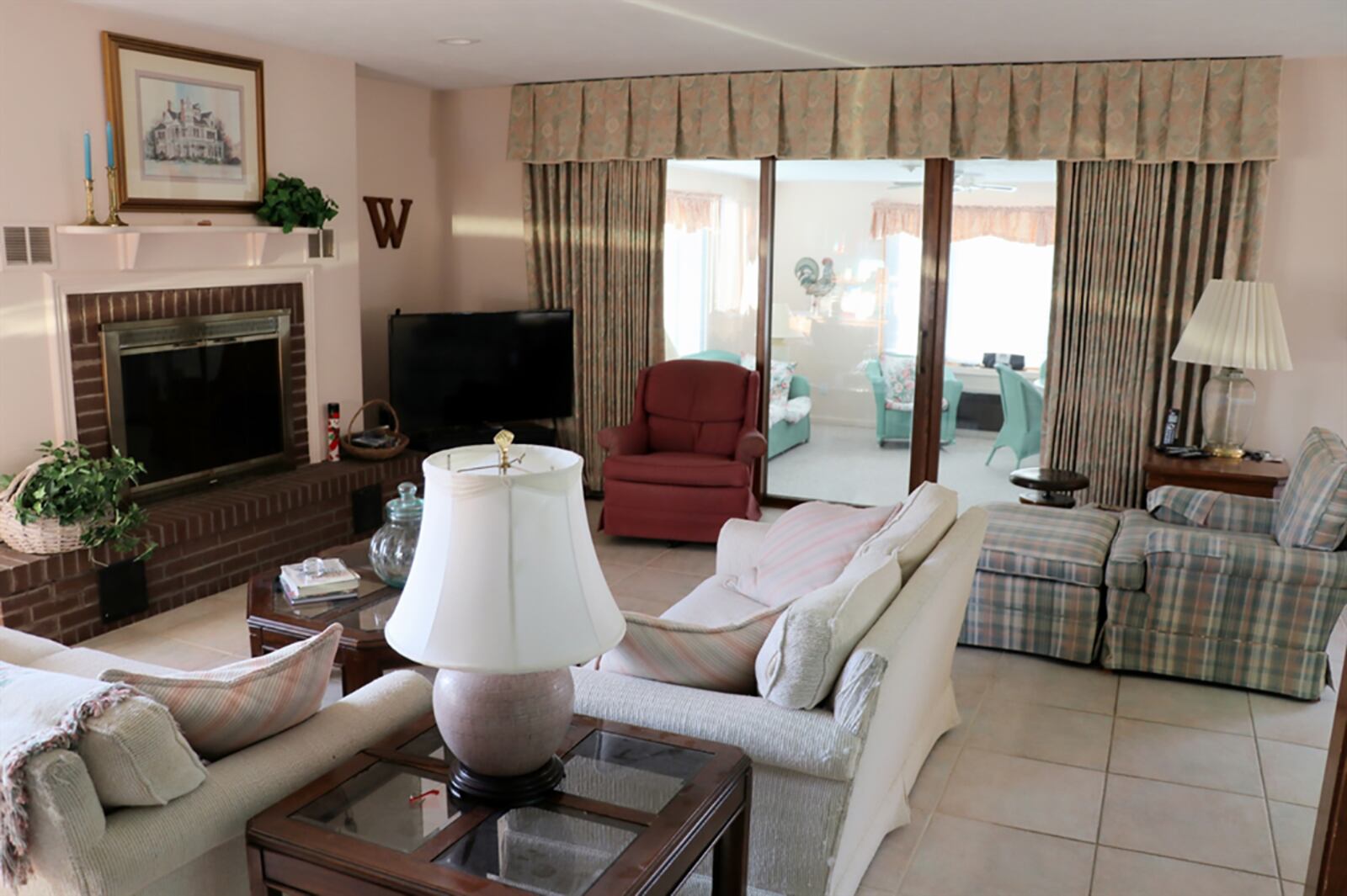 A gas fireplace with raised brick hearth and wood mantel is the centerpiece to the family room. Triple patio doors that open from the family room to a 4-season room. CONTRIBUTED PHOTO BY KATHY TYLER