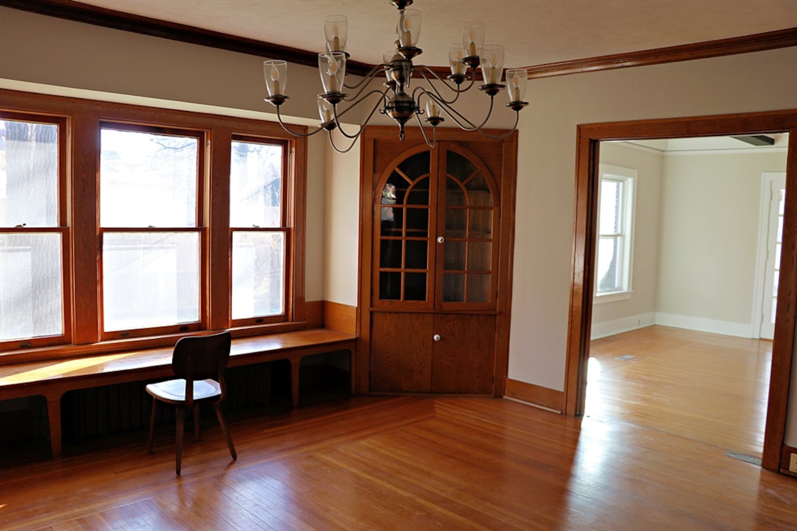 In the dining room, triple windows are flanked by built-in corner China cabinets. The top cabinet doors have arched glass windows. 