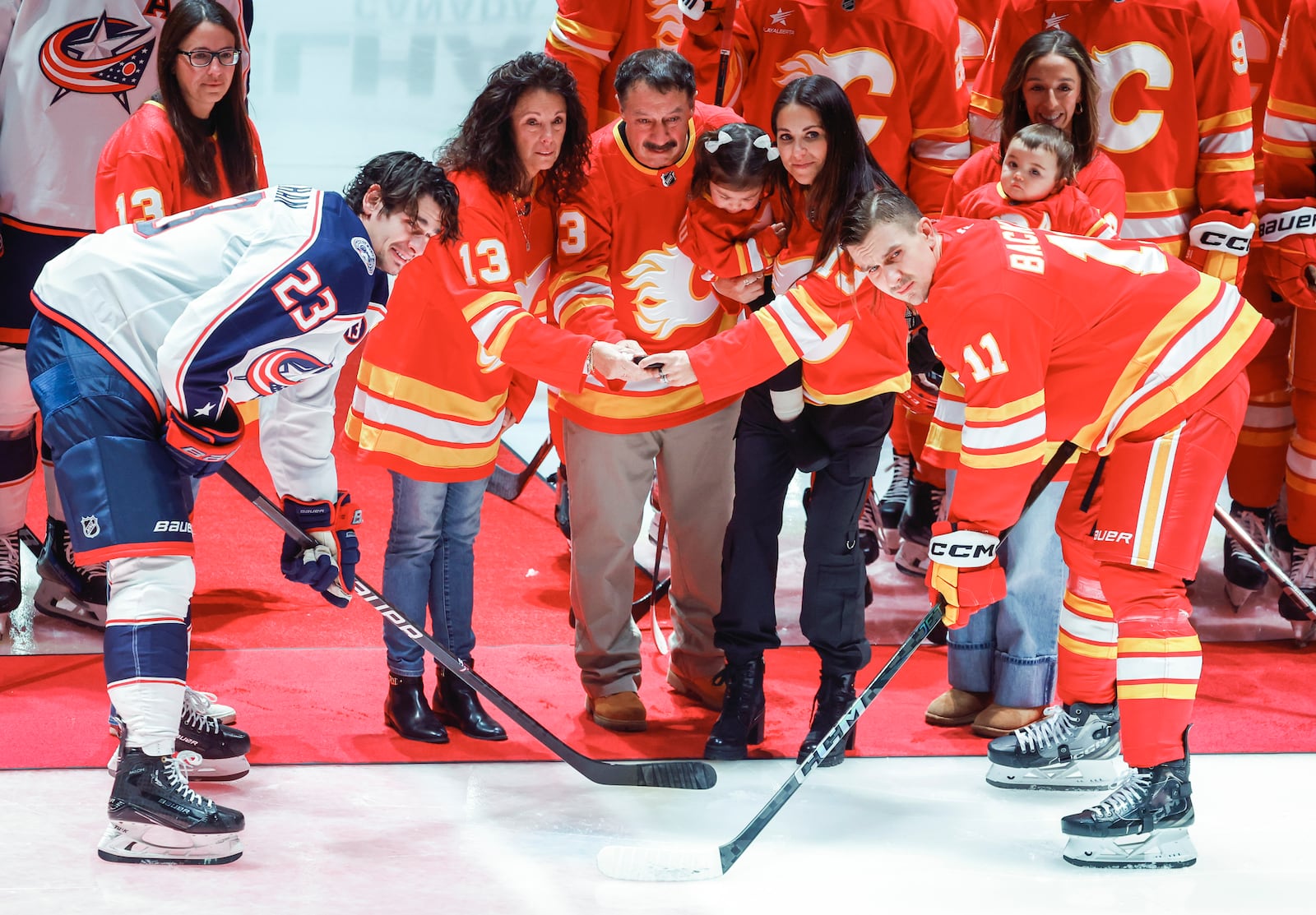 Columbus Blue Jackets' Sean Monahan, left, and Calgary Flames' Mikael Backlund join the family of Johnny Gaudreau at centre ice prior to first period NHL hockey action in Calgary on Tuesday, Dec. 3, 2024.THE CANADIAN PRESS/Jeff McIntosh/The Canadian Press via AP)