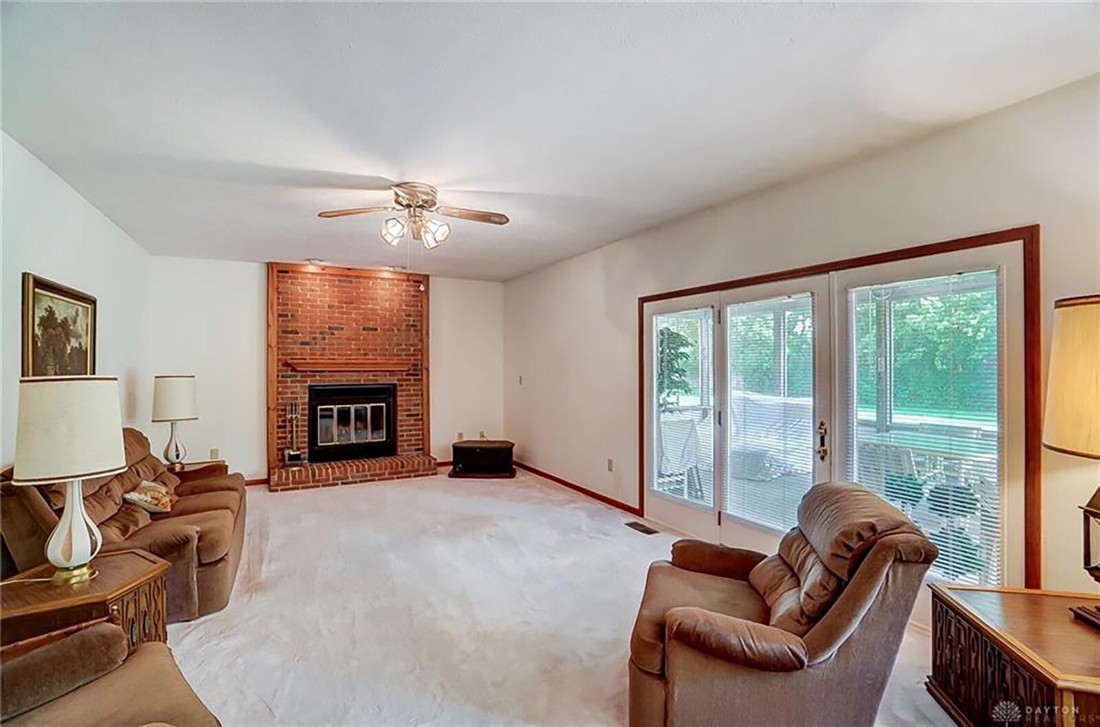 the sunken family room has neutral carpeting, a ceiling fan and a brick woodburning fireplace with glass doors. A sunroom is connected to this room and overlooks the back yard.