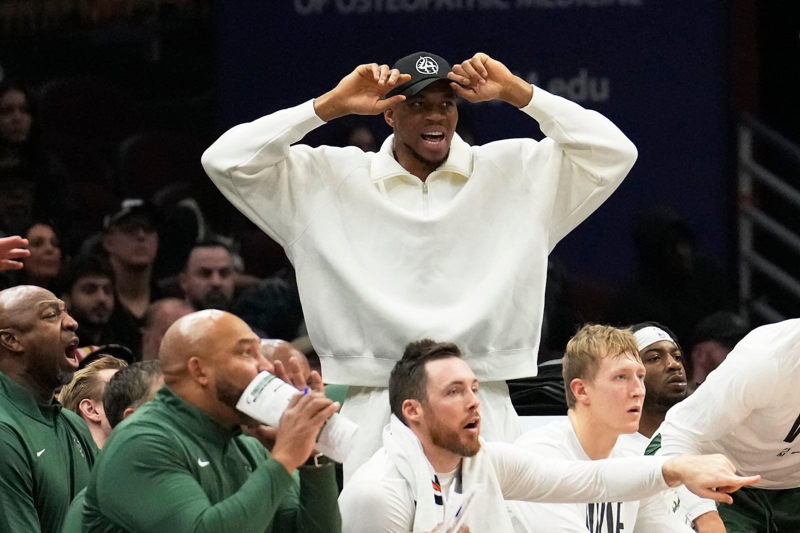 Injured Milwaukee Bucks forward Giannis Antetokounmpo watches from behind the bench in the first half of an NBA basketball game against the Cleveland Cavaliers, Monday, Nov. 4, 2024, in Cleveland. (AP Photo/Sue Ogrocki)