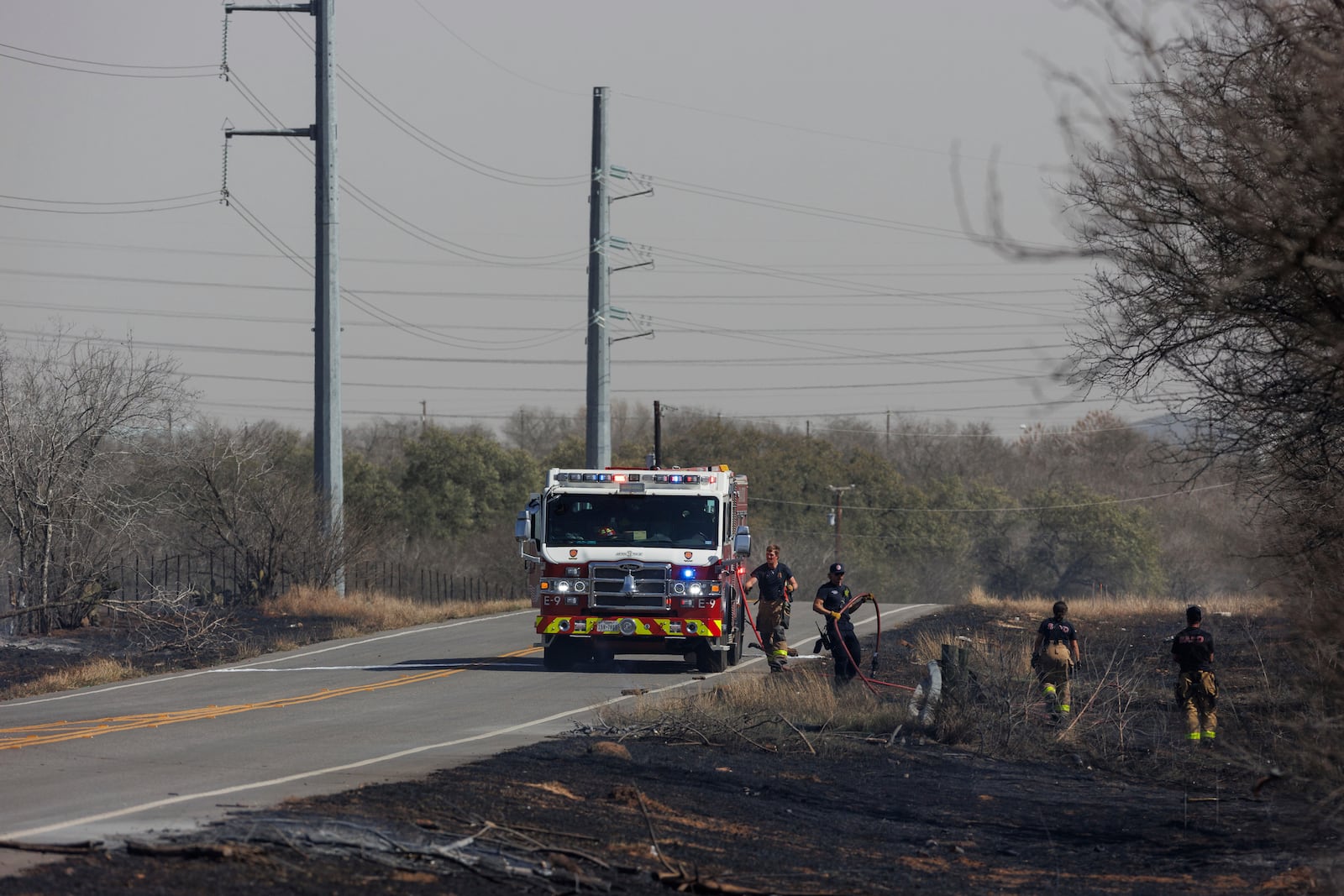 Firefighters work to put out brush fires along Southton Road, near Interstate 37, on the far southeast side of San Antonio, Tuesday, March 4, 2025. (Sam Owens/The San Antonio Express-News via AP)