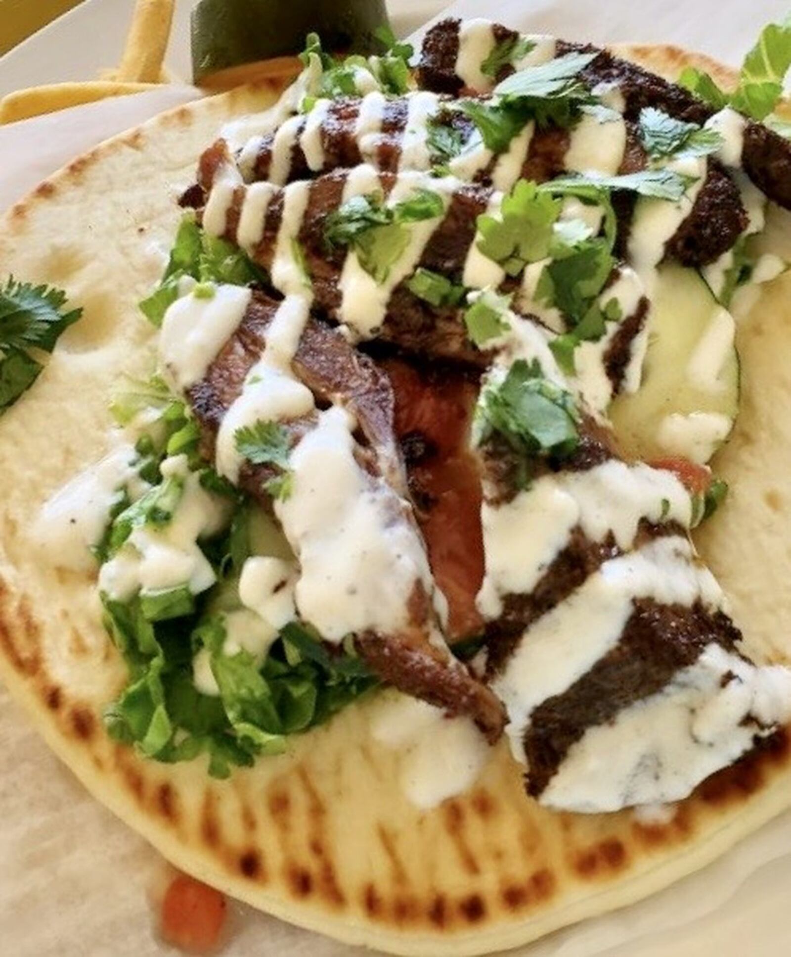 Meadowlark’s Mediterranean Spiced Lamb Pita Sandwich features spice-crusted, slow-roasted lamb breast is sliced and tucked into warm pita bread for a savory, satisfying sandwich, dressed generously with cucumber, tomato, cilantro and yogurt. CONTRIBUTED