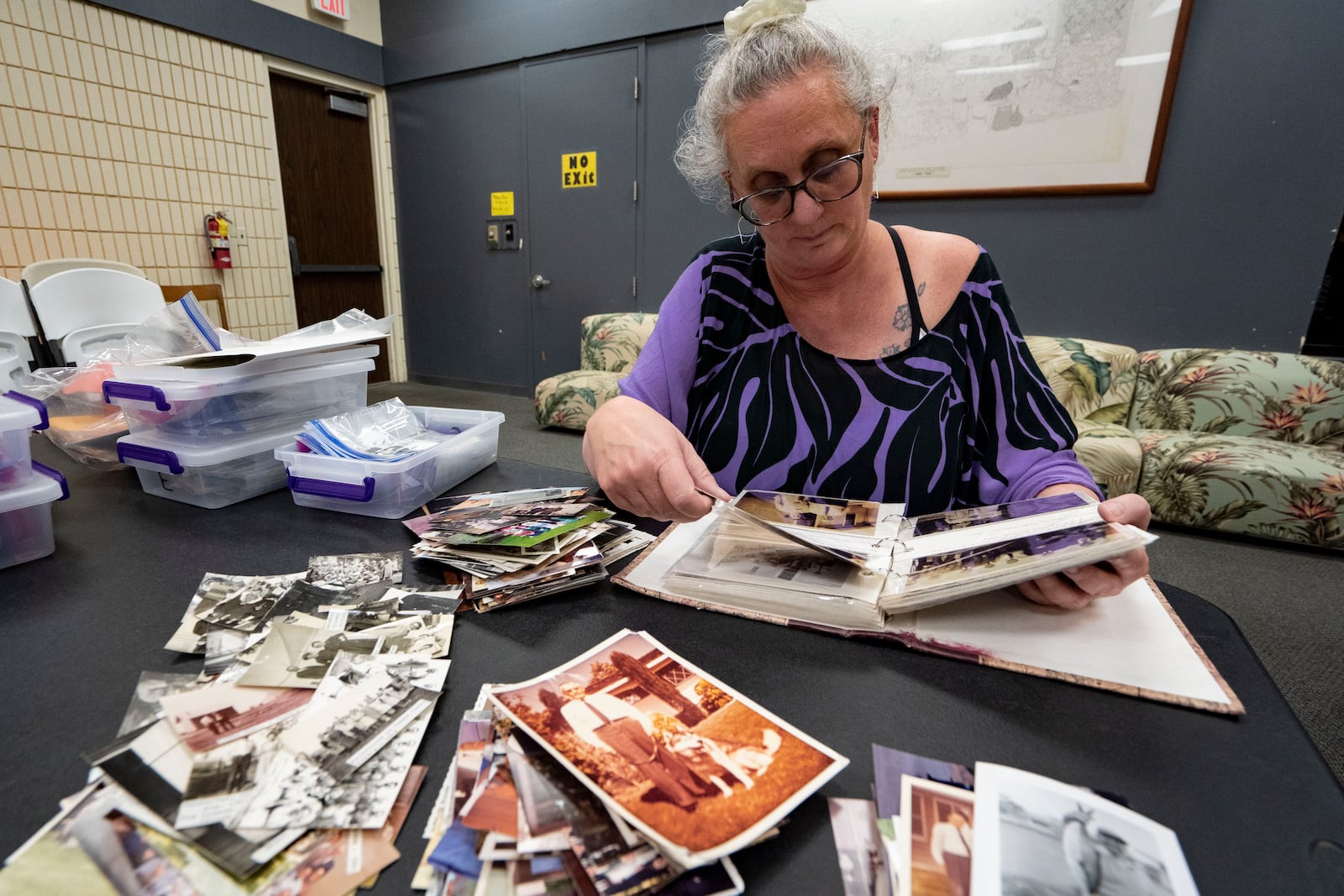 Pam Walton flips through an album containing photographs of “Two by Twos” members and ministers, or “workers,” at a library Monday, Dec. 9, 2024, in Wailea, Hawaii. (AP Photo/Mengshin Lin)