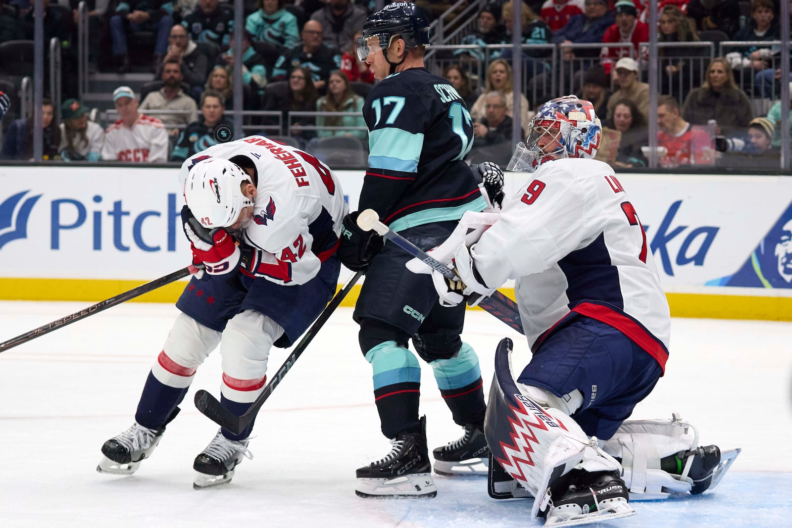 Washington Capitals defenseman Martin Fehervary (42) reacts after he was hit in the face by the puck as Seattle Kraken center Jaden Schwartz (17) and Capitals goaltender Charlie Lindgren (79) look on during the second period of an NHL hockey game, Thursday, Jan. 23, 2025, in Seattle. (AP Photo/John Froschauer)