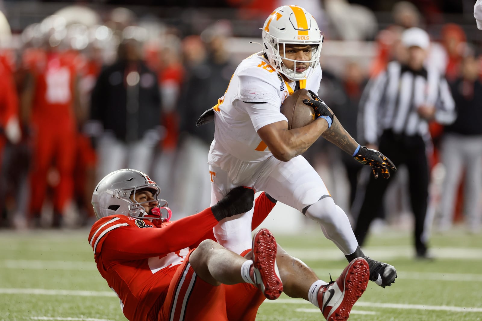 Tennessee running back DeSean Bishop, top, tries to run past Ohio State defensive lineman JT Tuimoloau, bottom, during the first half in the first round of the College Football Playoff, Saturday, Dec. 21, 2024, in Columbus, Ohio. (AP Photo/Jay LaPrete)