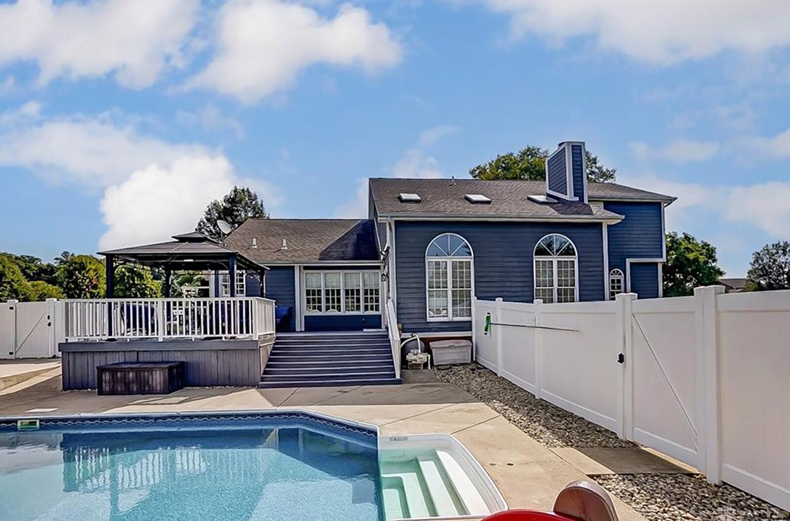 The rear of the home has a wood raised deck with pergola and railings over looking the pool.