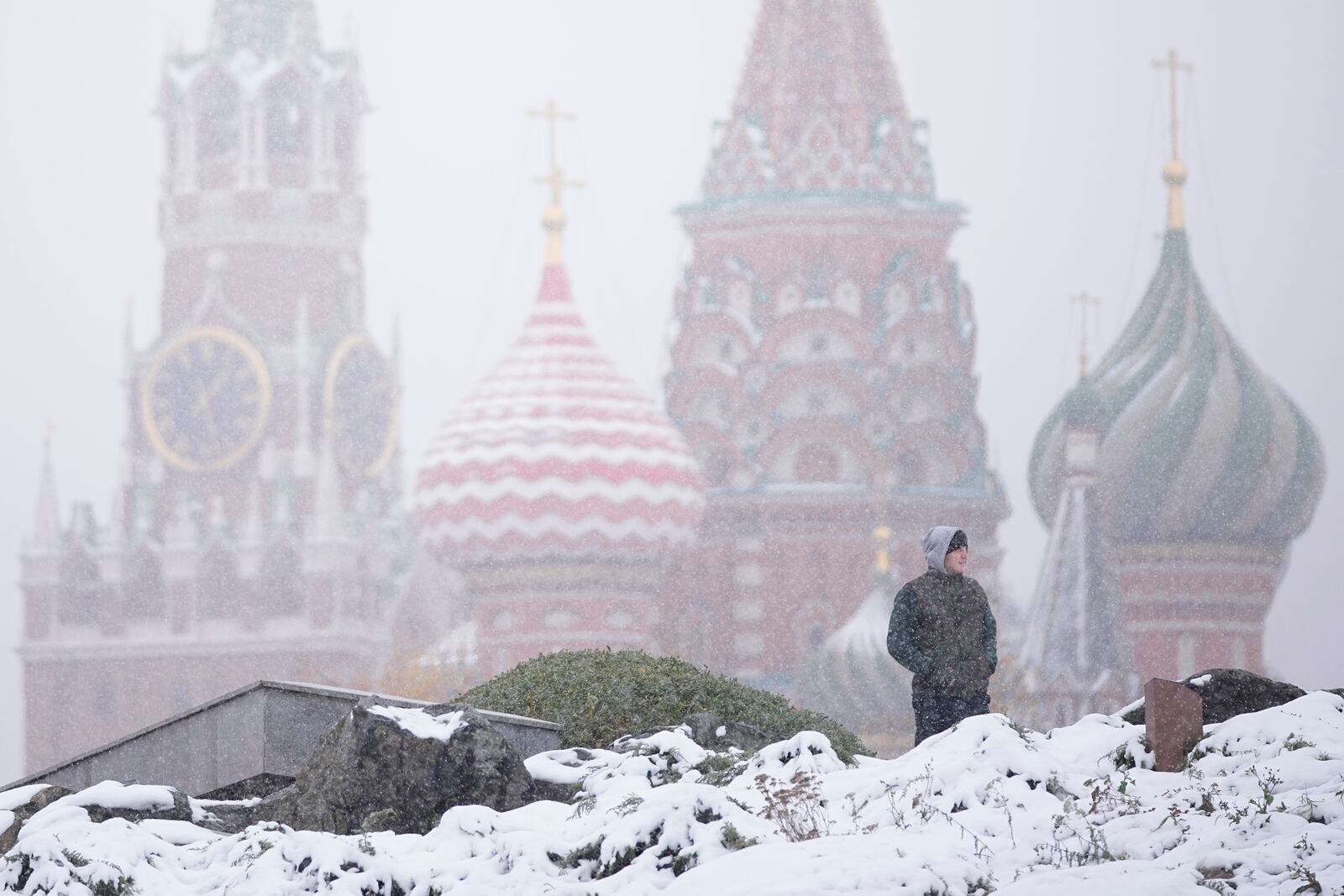 A man walks at Zaryadye park with the Spasskaya tower of the Kremlin and St. Basil's Cathedral in the background during a snowfall in Moscow, Russia, Wednesday, Nov. 6, 2024. (AP Photo/Pavel Bednyakov)