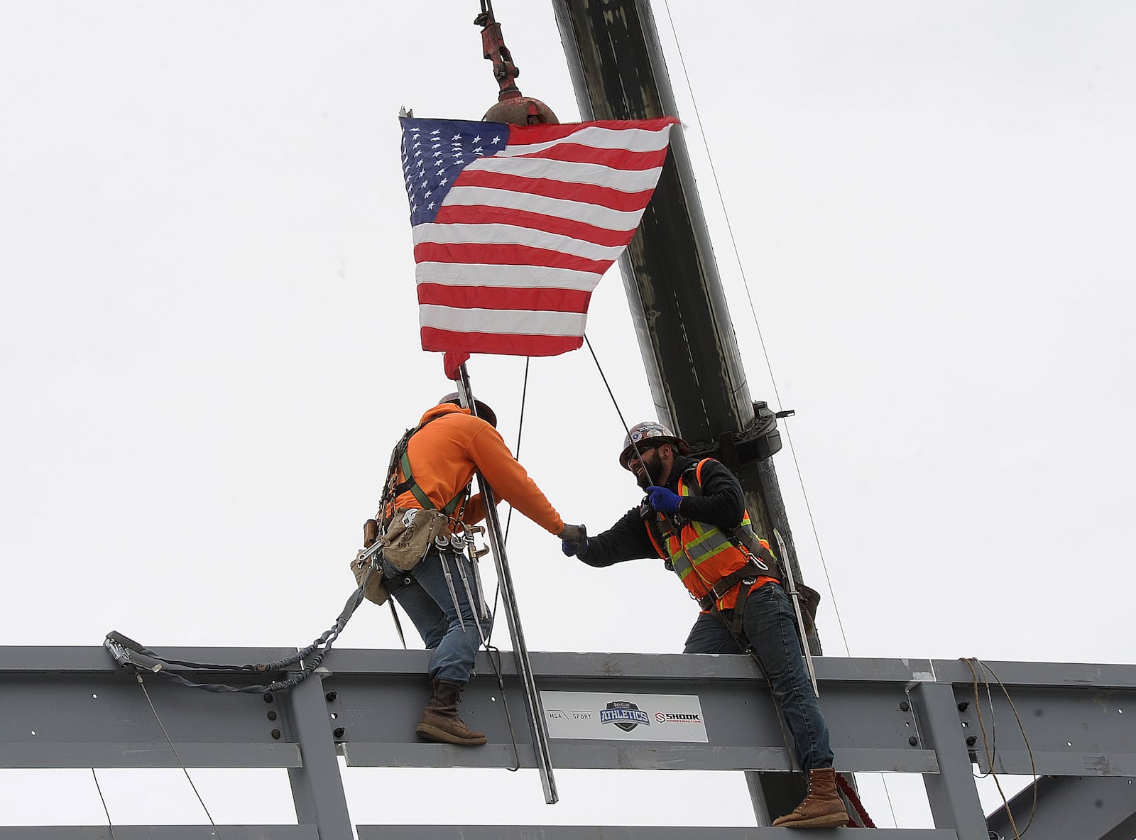 Workers shake hands Thursday April 6, 2023 after placing the final beam on the new press box at Welcome Statium. MARSHALL GORBY\STAFF