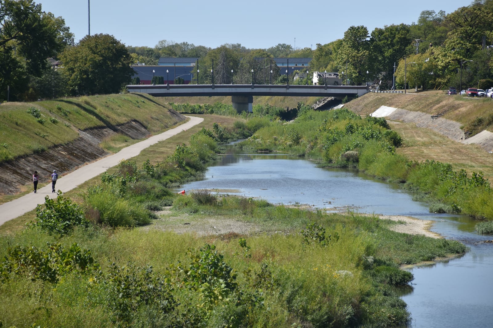 Two people on scooters ride along the Wolf Creek Trail on the southside of the Wolf Creek tributary. The city of Dayton wants to redesign sections of the flood protection levees on either side of Wolf Creek to create new ways to access the waterway. CORNELIUS FROLIK / STAFF