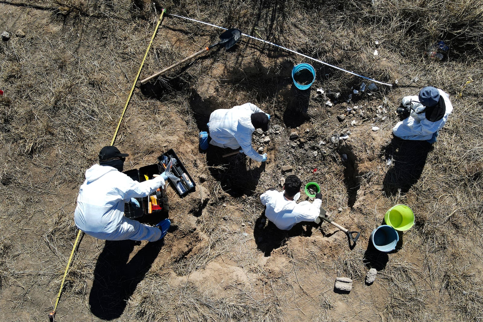 FILE - Forensic technicians excavate a field on a plot of land referred to as a cartel "extermination site" where burned human remains are buried, on the outskirts of Nuevo Laredo, Mexico, Feb. 8, 2022. (AP Photo/Marco Ugarte, File)