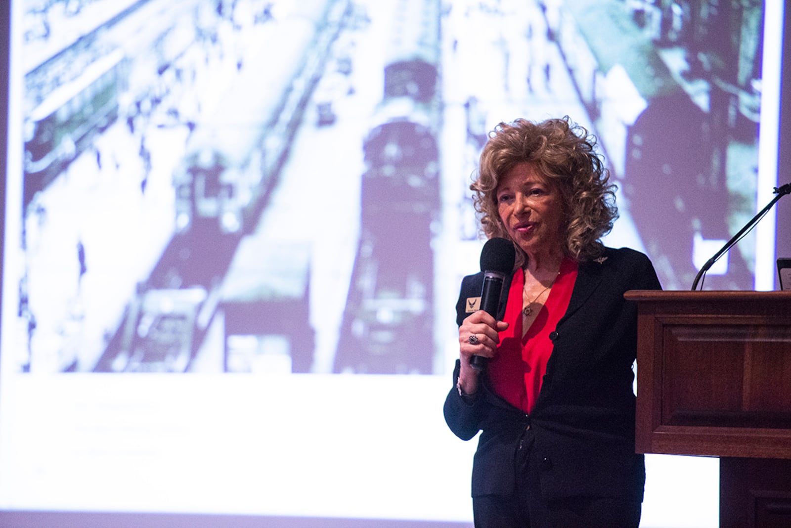 Dr. Renate Frydman delivers remarks as keynote speaker during the Holocaust Remembrance Day event on April 8 at the National Museum of the U.S. Air Force on Wright-Patterson Air Force Base. Frydman said her first memory as a child was boarding a train at Frankfurt Train Station (shown on the screen) to escape Nazi Germany. U.S. AIR FORCE PHOTO/WESLEY FARNSWORTH