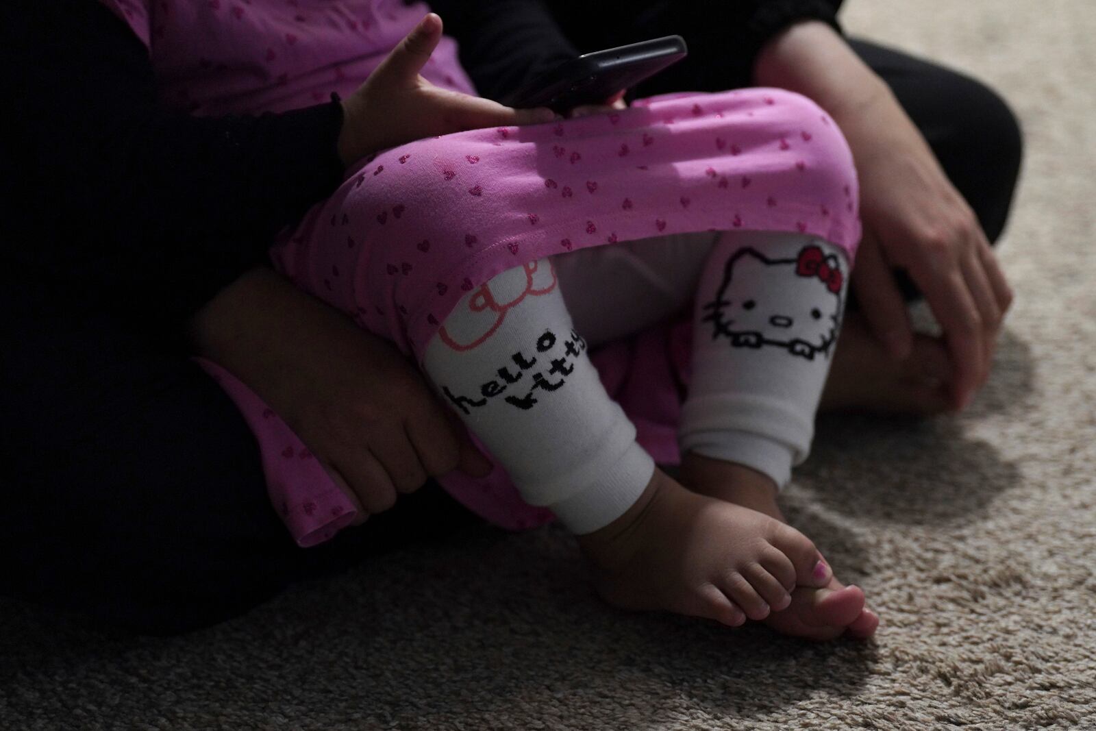 Rahmani's young daughter and wife sit together in their apartment in Laurel, Md., Monday, March 3, 2025. The family moved to the U.S. in November with the federal refugee program, a vetted form of legal migration to the U.S. for those fleeing persecution. (AP Photo/Jessie Wardarski)