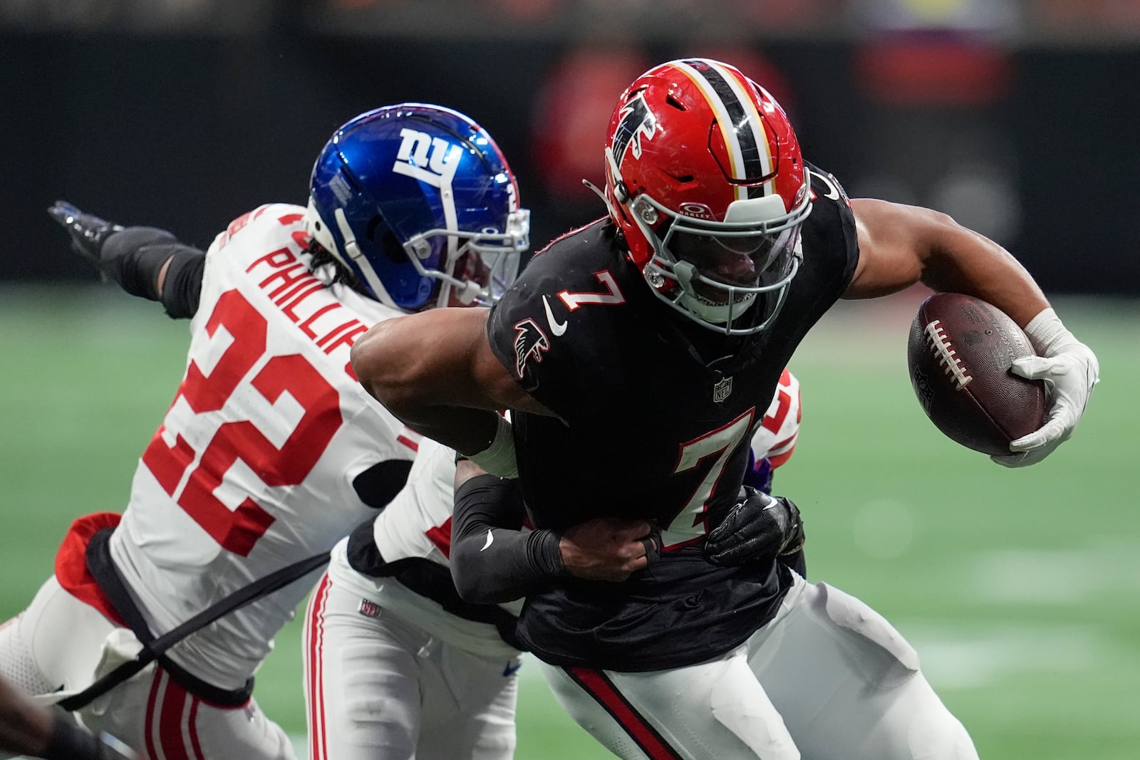 Atlanta Falcons running back Bijan Robinson (7) runs the ball against New York Giants cornerbacks Cor'Dale Flott (28) and Dru Phillips (22) in the second half of an NFL football game in Atlanta, Sunday, Dec. 22, 2024. (AP Photo/Mike Stewart)