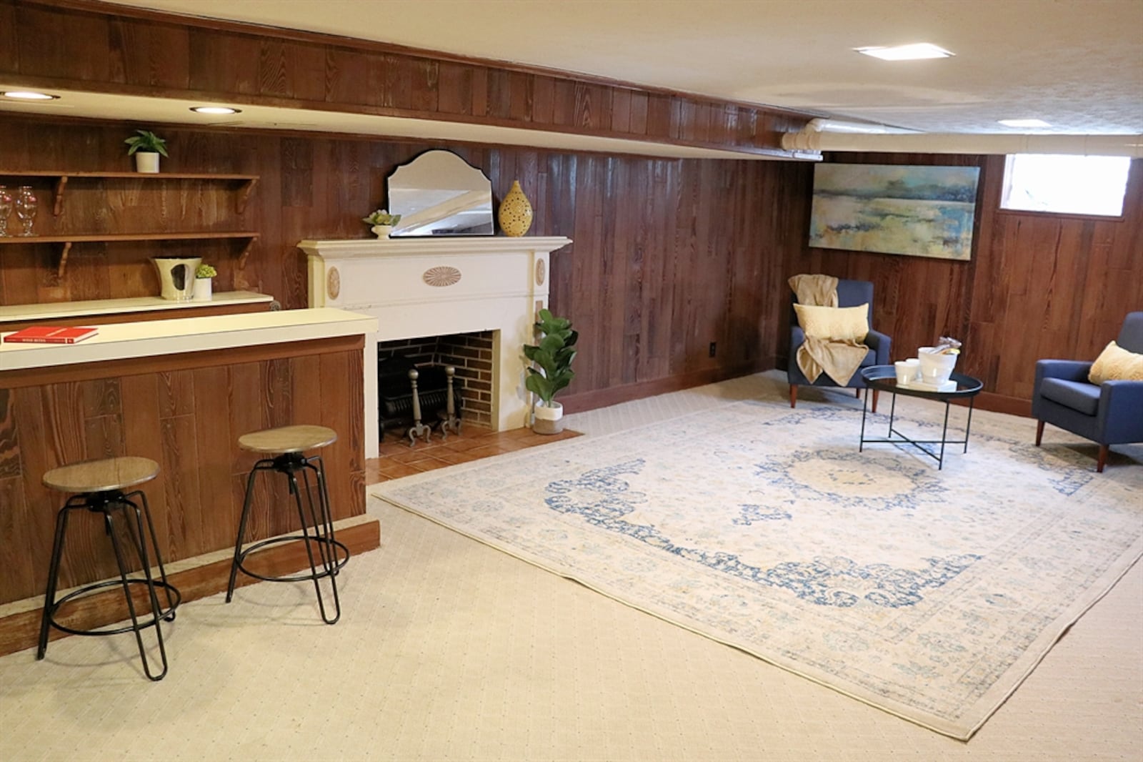 The home features a large family room with a decorative fireplace and a peninsula dry bar. Wood paneling covers the walls.