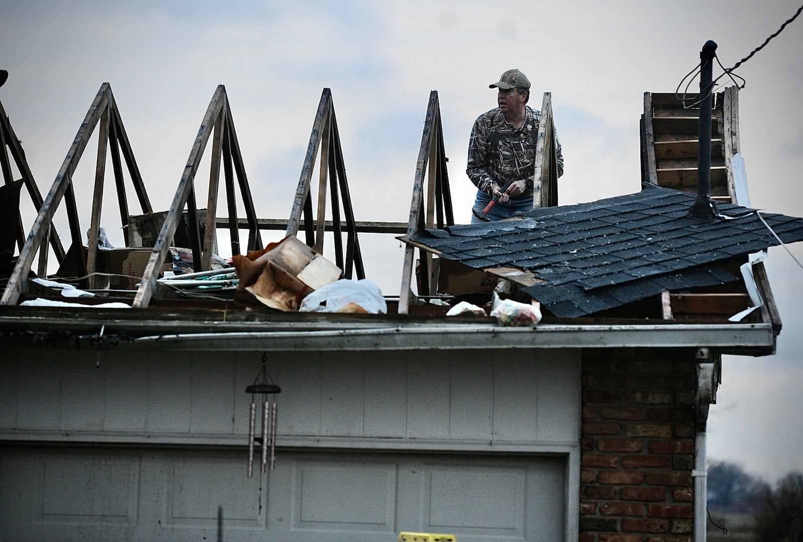 Ted Williams works to put a temporary cover on the roof after a tornado struck his in-laws' home on Newlove Road Wednesday morning, Feb. 28, 2024. William said his in-laws stayed in the middle hallway and both are safe. MARSHALL GORBY/STAFF