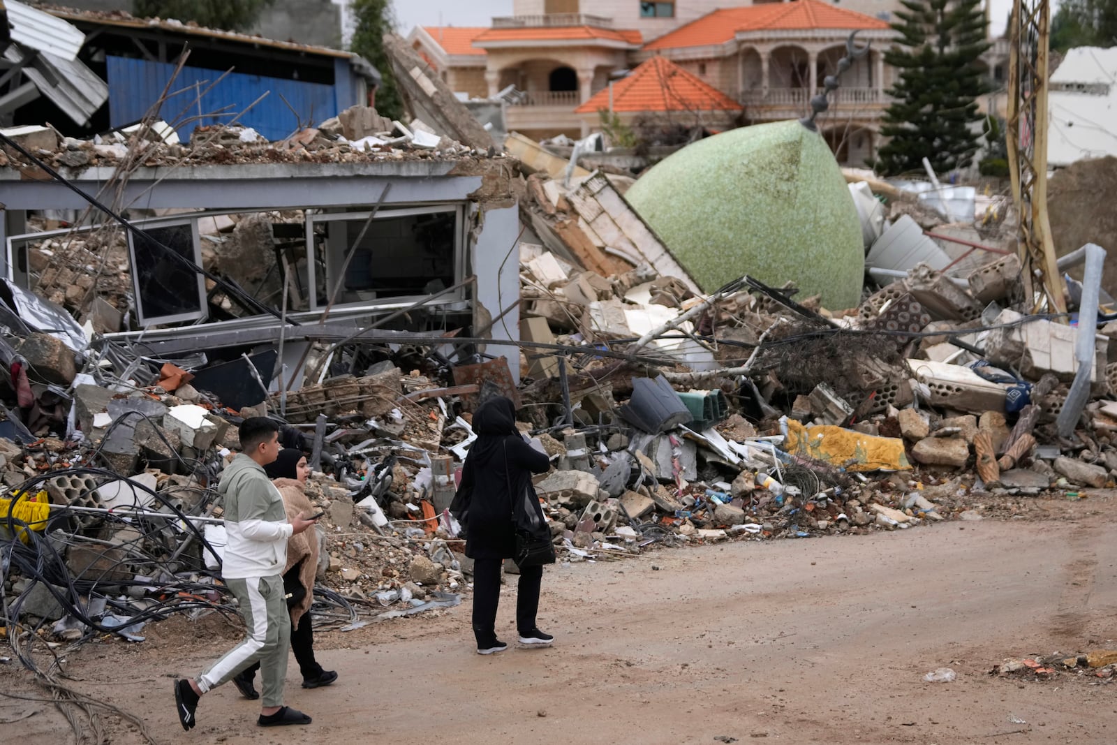 Displaced residents returning to their village, walk past a destroyed mosque, in the town of Bint Jbeil, southern Lebanon, following a ceasefire between Israel and Hezbollah that went into effect on Wednesday, Nov. 27, 2024. (AP Photo/Hussein Malla)