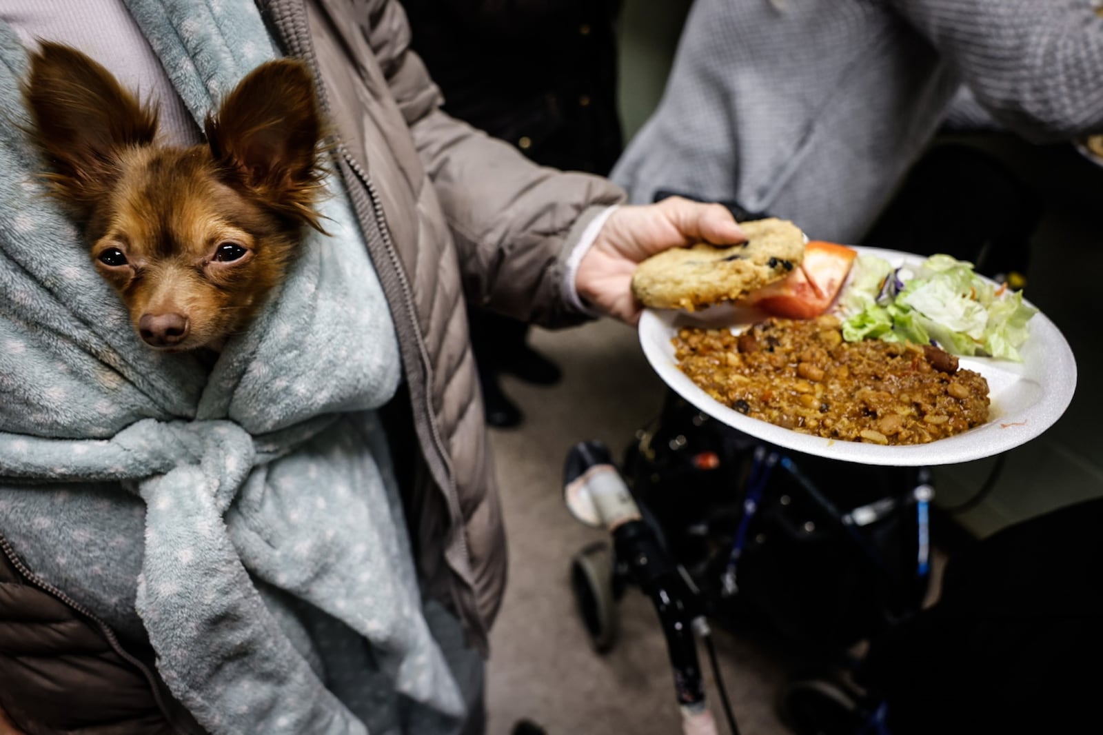 Woo Woo, a miniature chihuahua, is carried by a guest at St. Vincent de Paul Shelter for Women and Families on Apple Street in Dayton Tuesday, Feb. 14, 2023. A record amount of guests at the shelter reflects the growing number of homeless in the Dayton area.