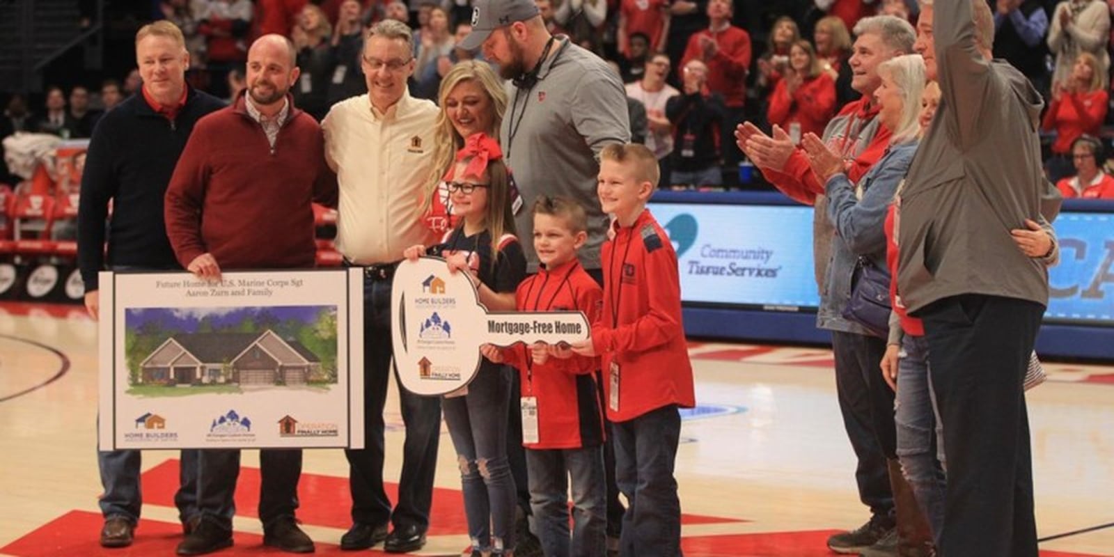 Aaron Zurn and his family are presented with a photo of a new home that will be built for them in Vandalia. (David Jablonski, daytondailynews.com)