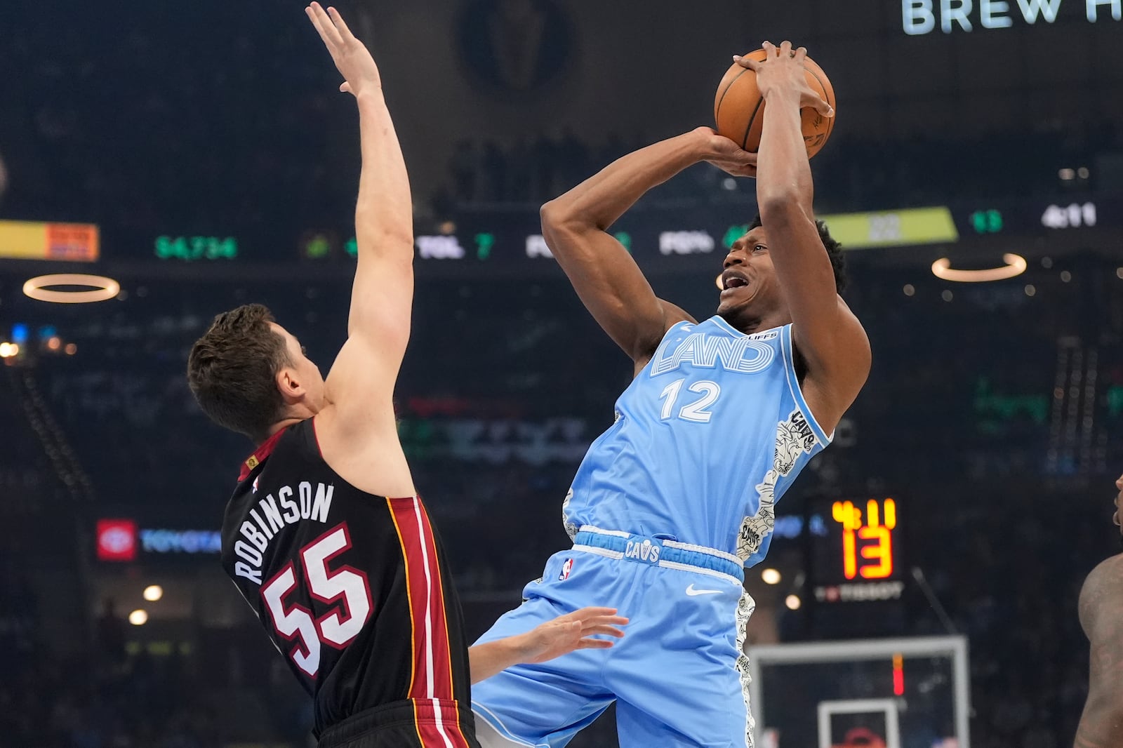 Cleveland Cavaliers forward De'Andre Hunter (12) shoots as Miami Heat forward Duncan Robinson (55) defends in the first half of an NBA basketball game Wednesday, March 5, 2025, in Cleveland. (AP Photo/Sue Ogrocki)