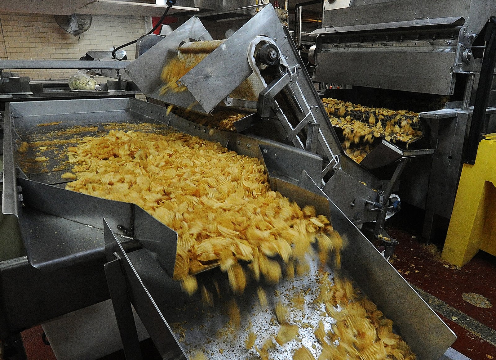 Freshly cooked groovy Mikesell's Potato chips roll along the cenveyor belt Thursday Dec. 1, 2022. MARSHALL GORBY\STAFF