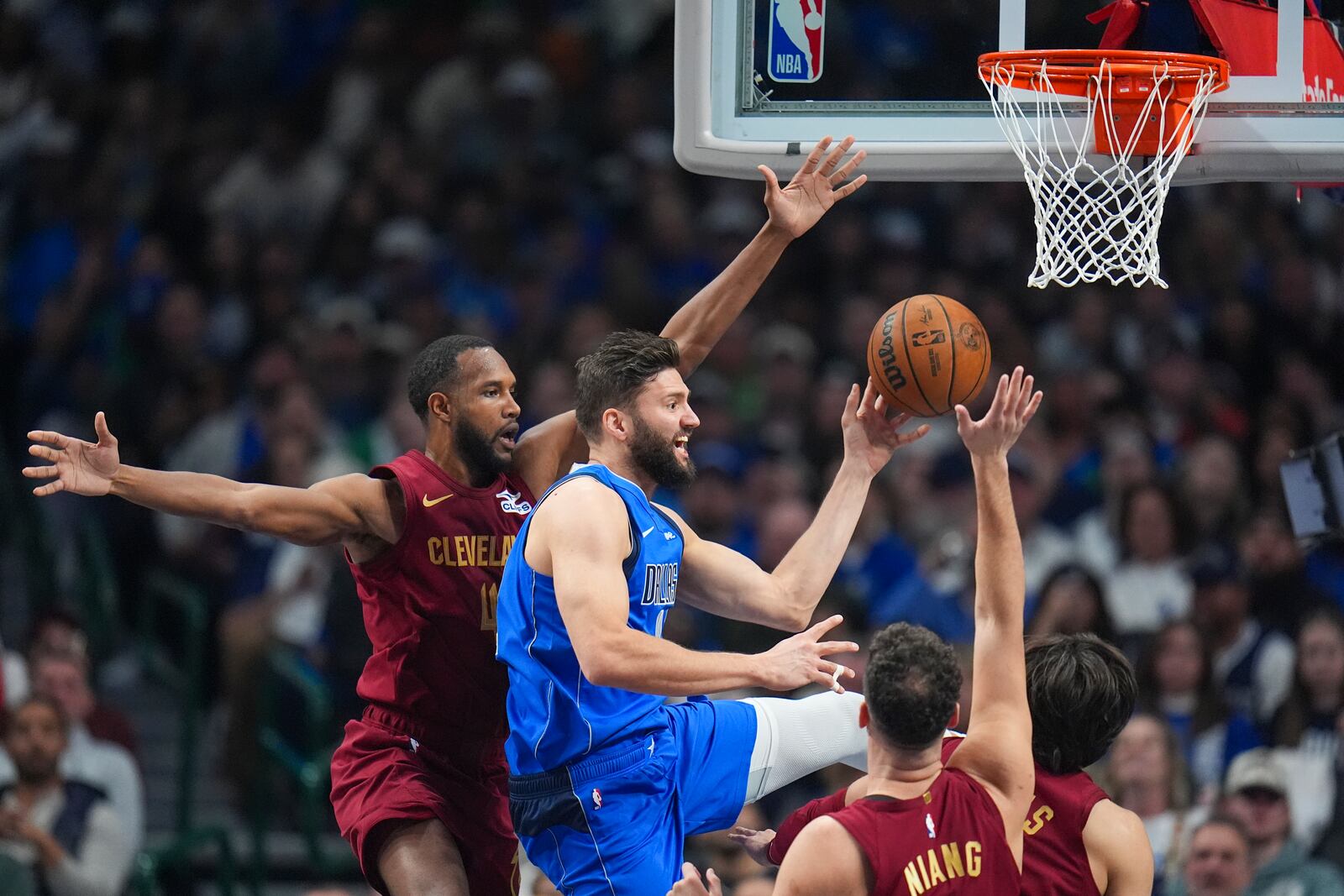 Dallas Mavericks forward Maxi Kleber, center, makes a pass as Cleveland Cavaliers forward Evan Mobley, left, and teammates defend during the first half of an NBA basketball game, Friday, Jan. 3, 2025, in Dallas. (AP Photo/Julio Cortez)