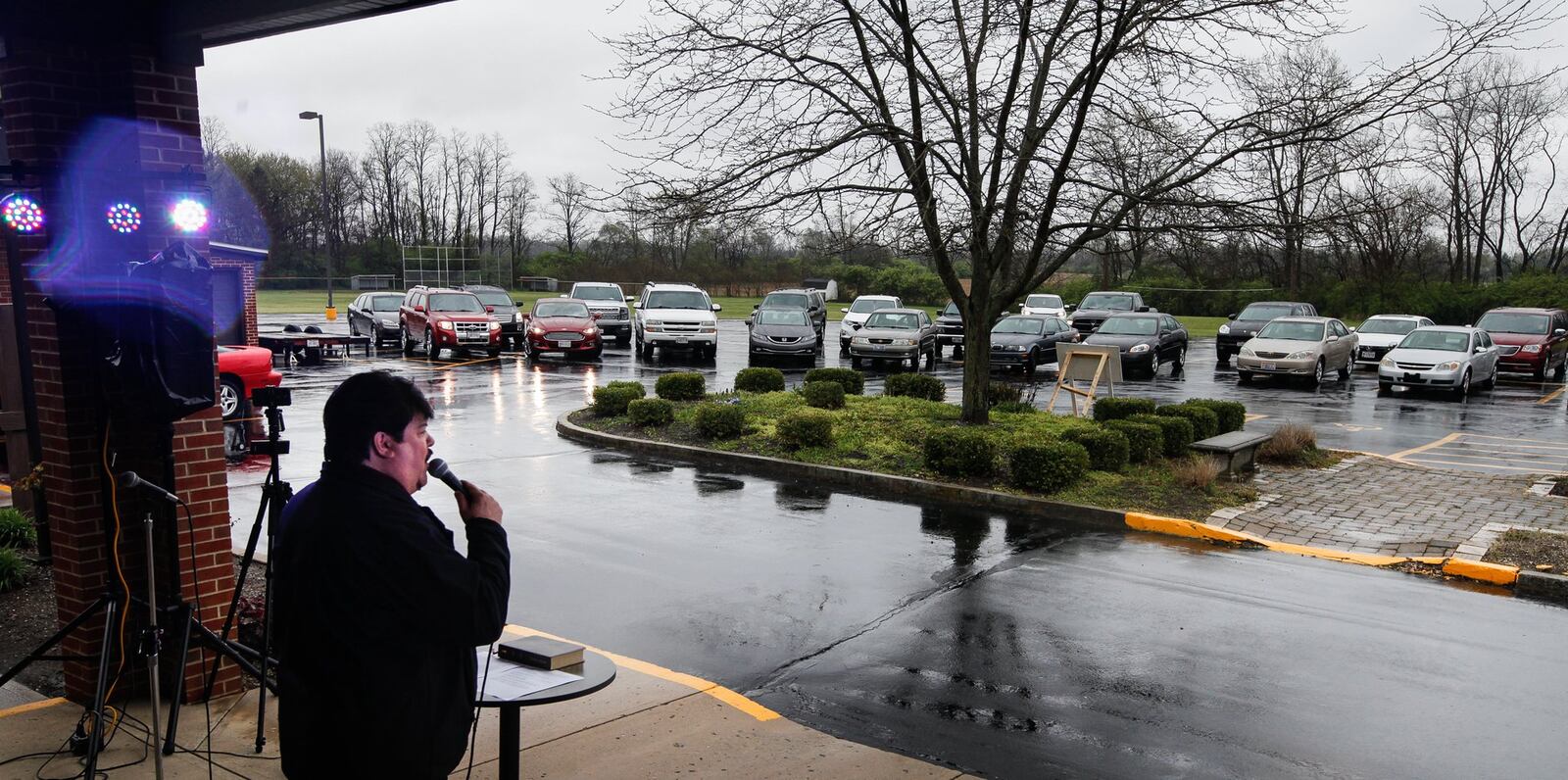 Bruce Jackson, pastor of First Grace Church in Butler Twp., told those gathered in vehicles Sunday to flash their lights to clap and honk horns to “praise the Lord.” CHRIS STEWART / STAFF