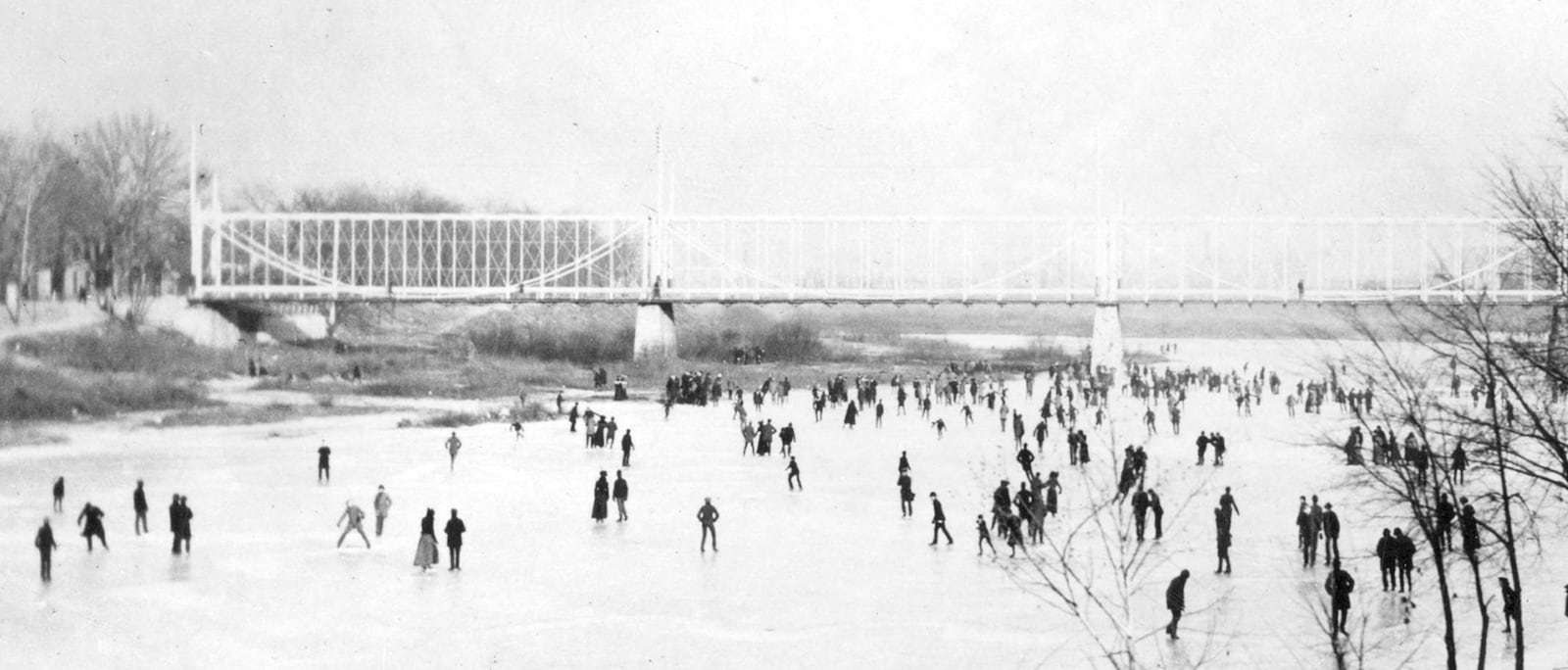 Ice skating on the Miami River on January 2, 1901.  On this day the ice was twelve inches thick.  Picture taken from the bank of the Miami River looking east toward the Main Street Bridge.  The old steel bridge was replaced in 1902 by a steel and concrete bridge. DAYTON METRO LIBRARY